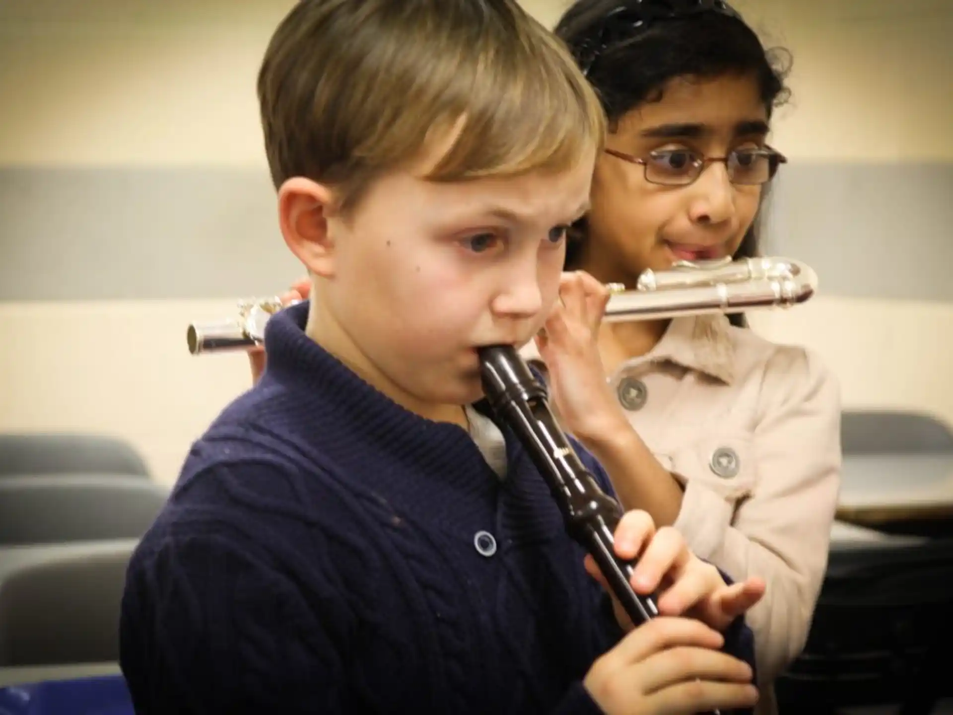 a boy holding a pipe to his mouth and another boy holding a pipe