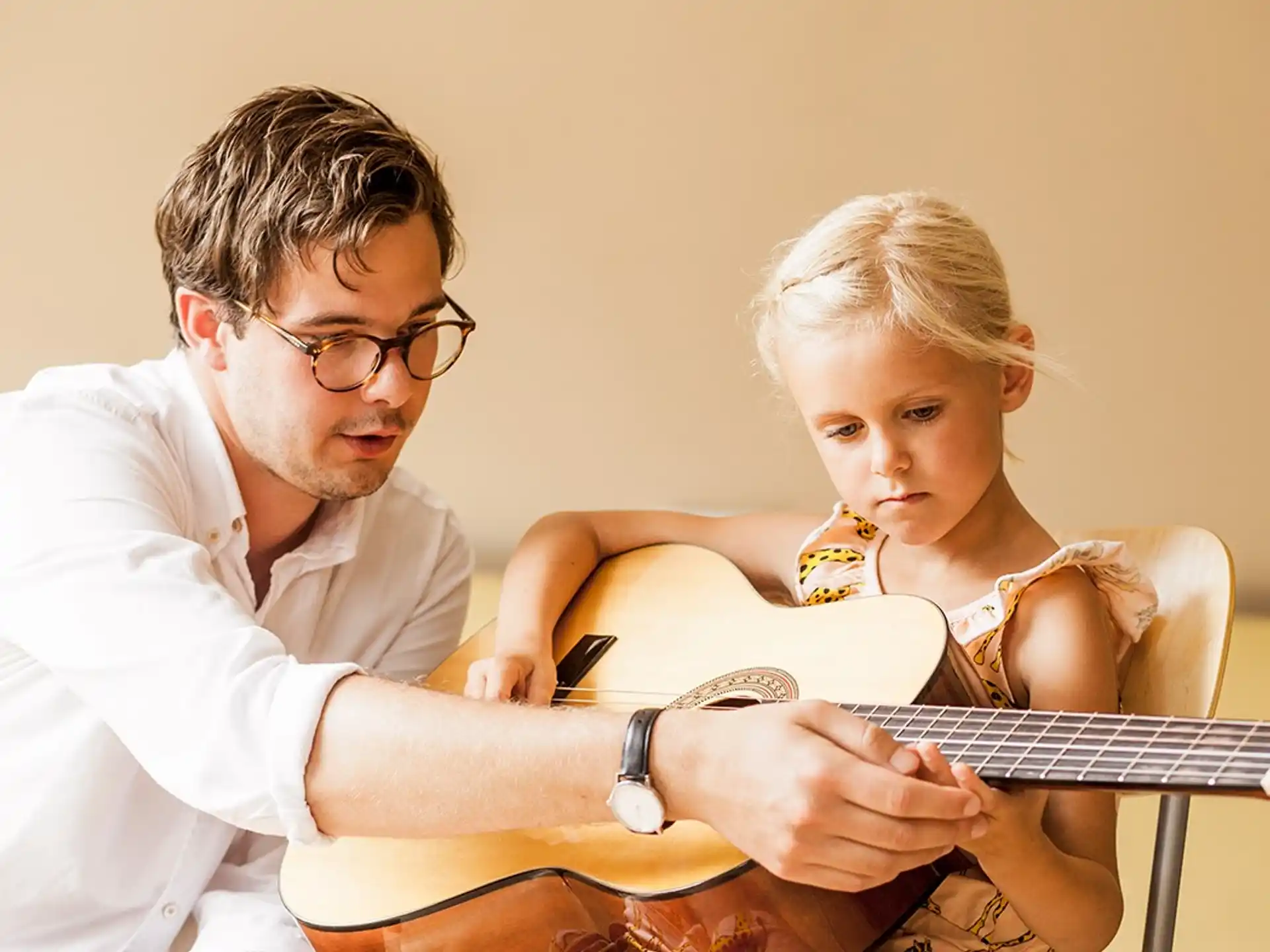 a person and a child playing a guitar
