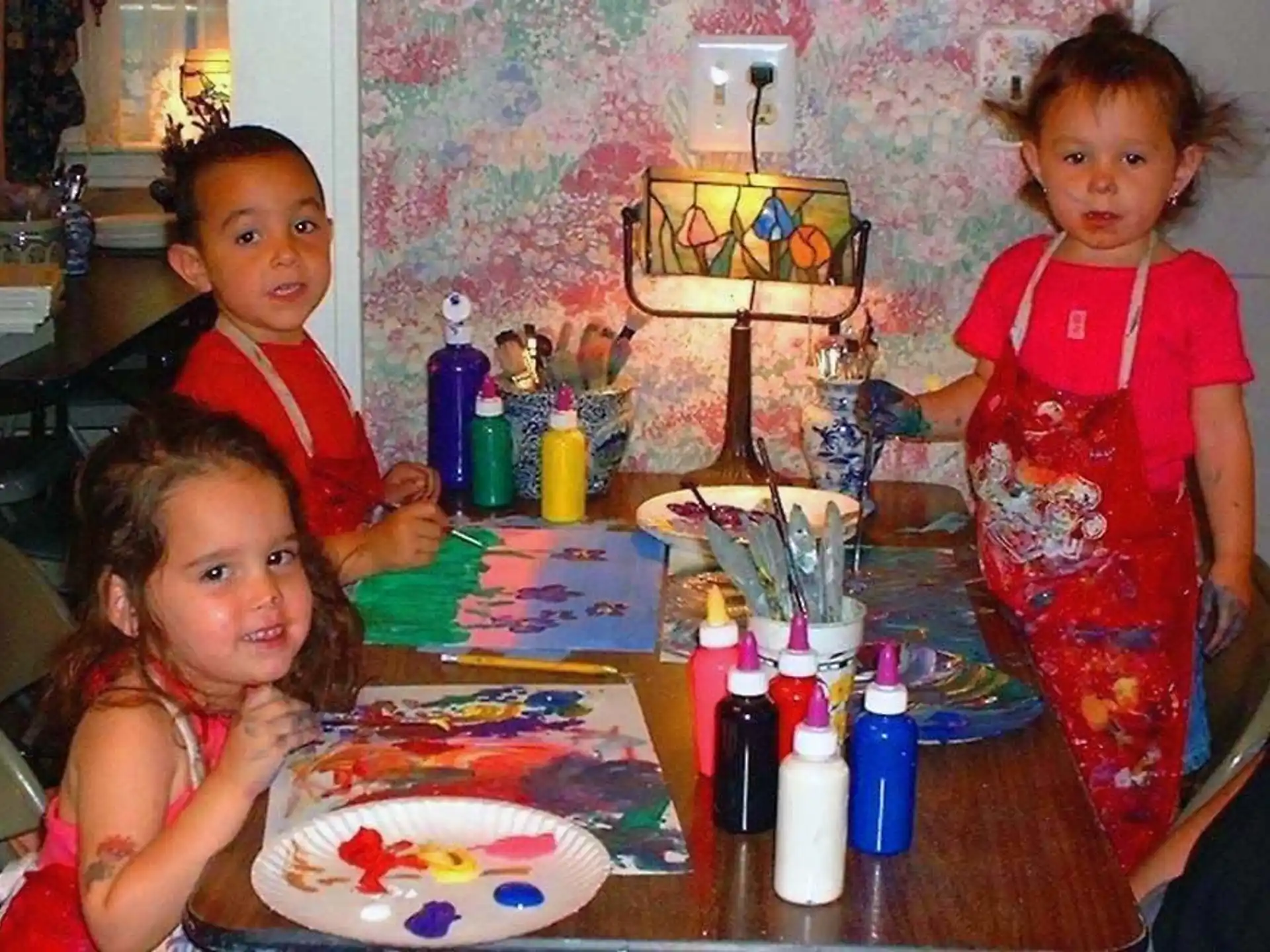 a group of children sitting at a table with food and drinks