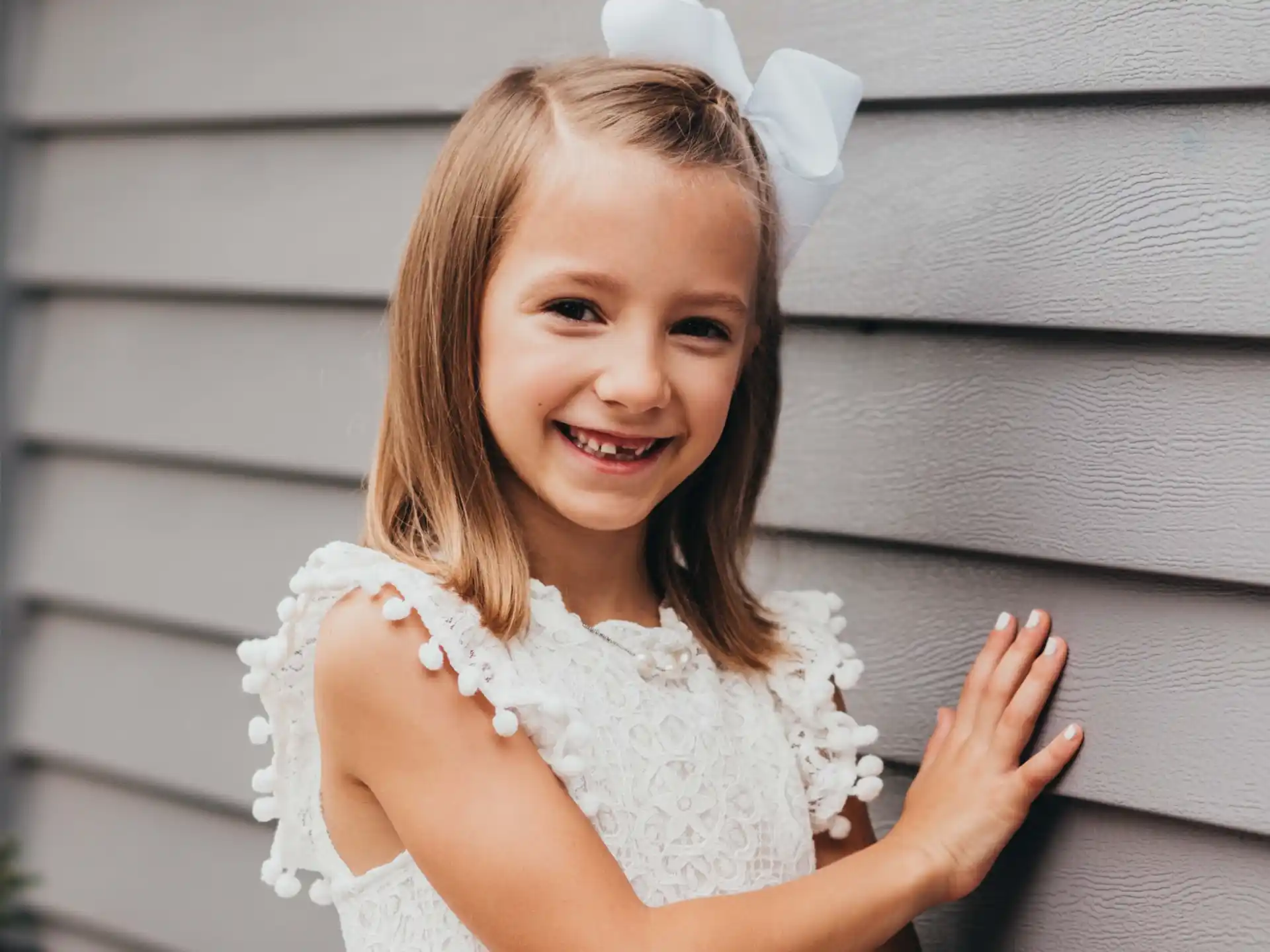 a girl wearing a white dress and smiling at the camera