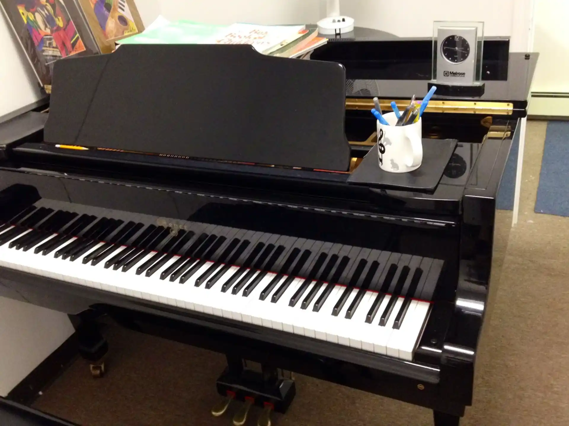 a black piano with a white cup on top of it