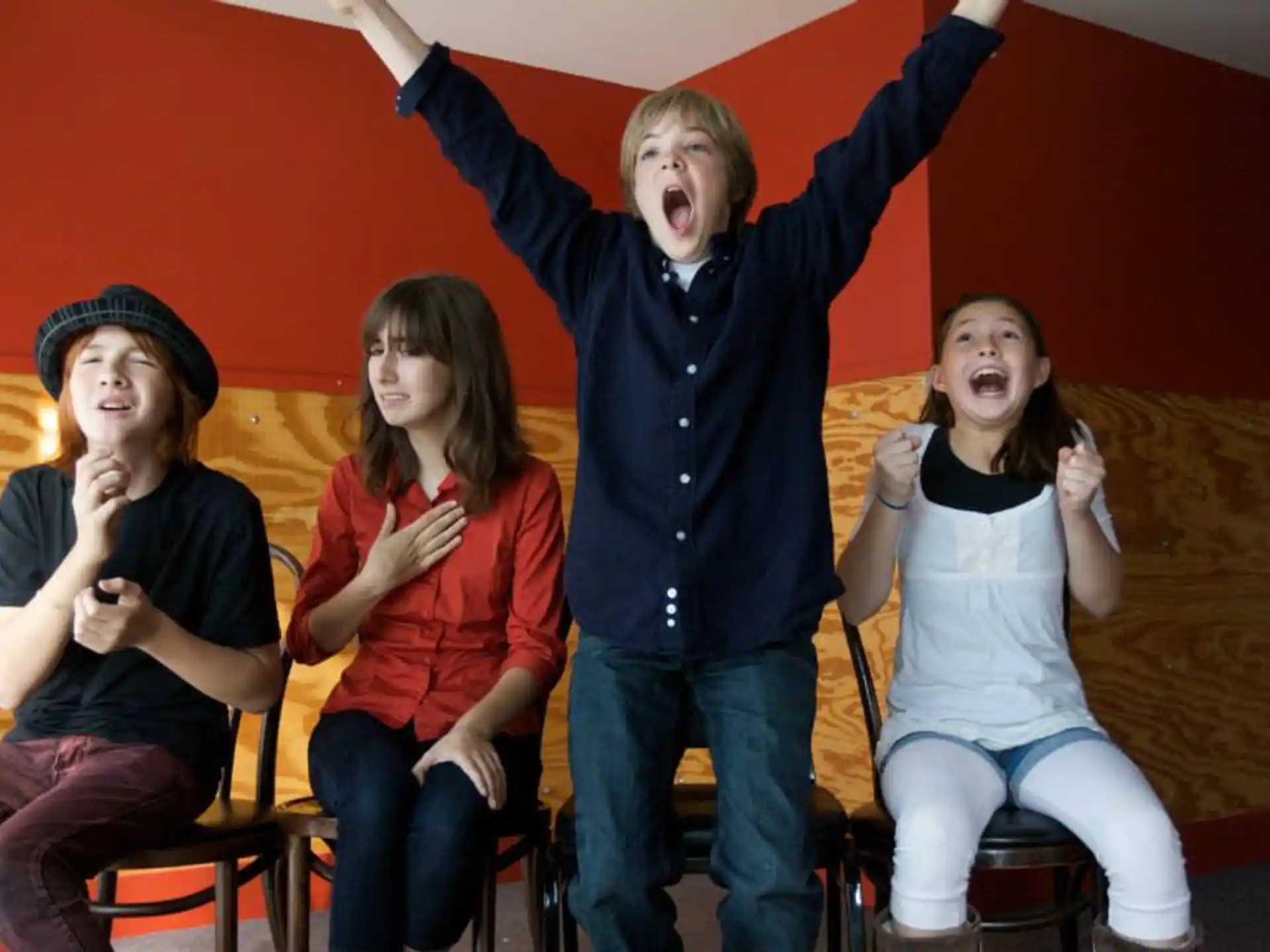 a group of people sitting on stools with their arms raised