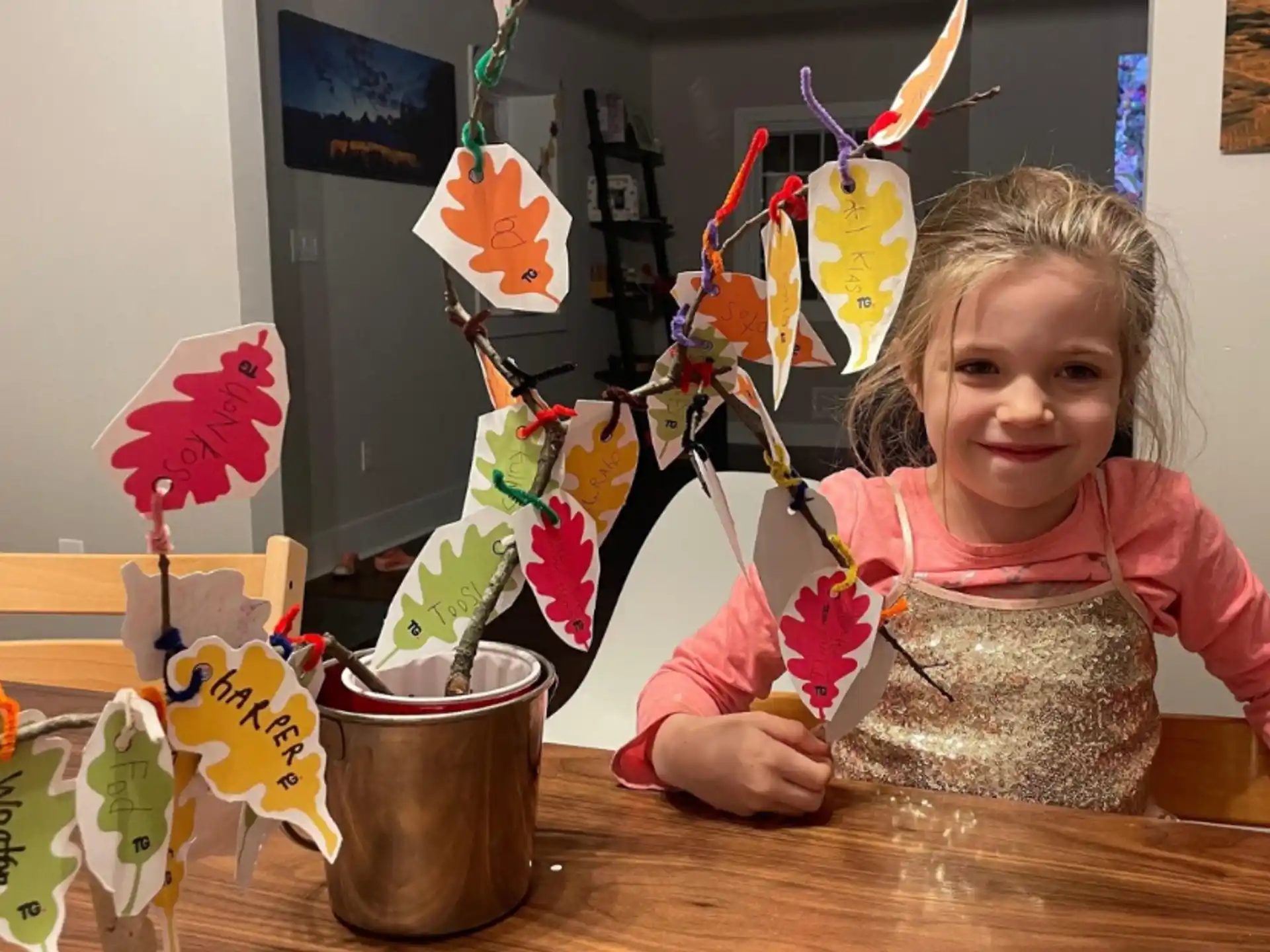 a girl sitting at a table with a plant in a pot