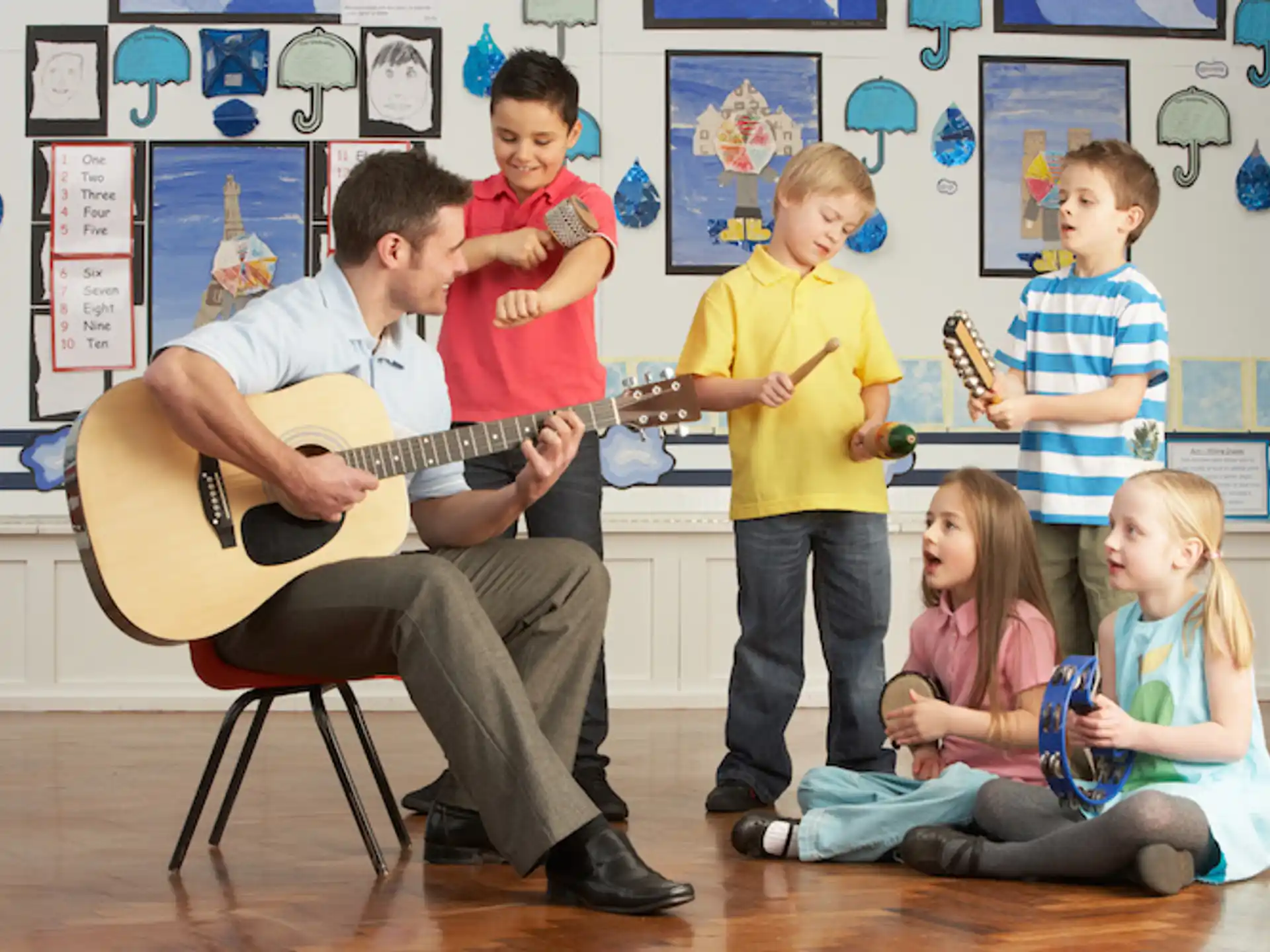 a person playing guitar in front of a group of children
