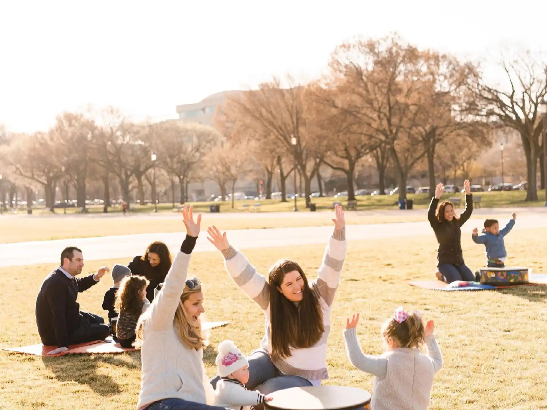 a group of people sitting on the grass with their arms raised