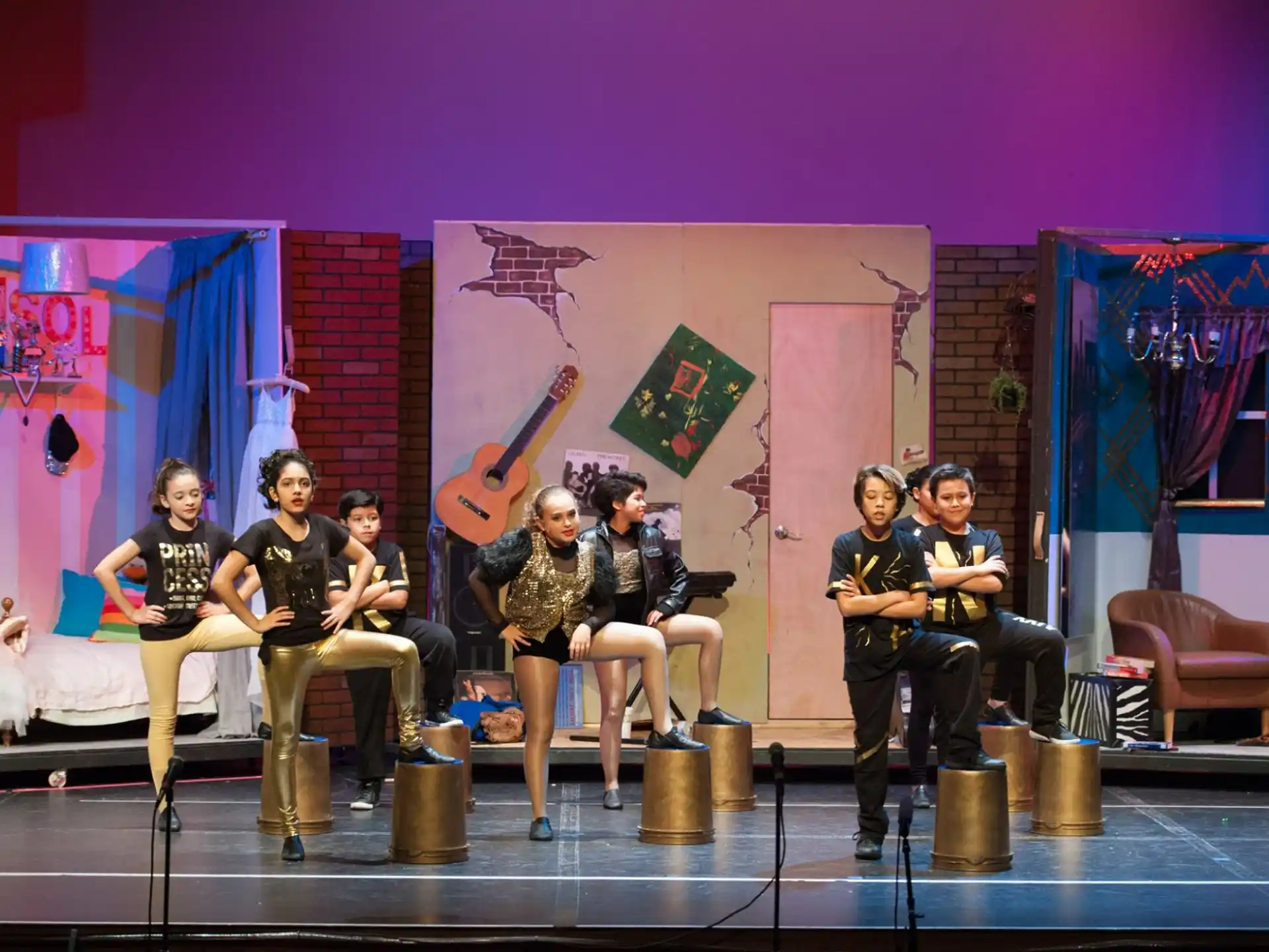 a group of people sitting on stools in front of a stage