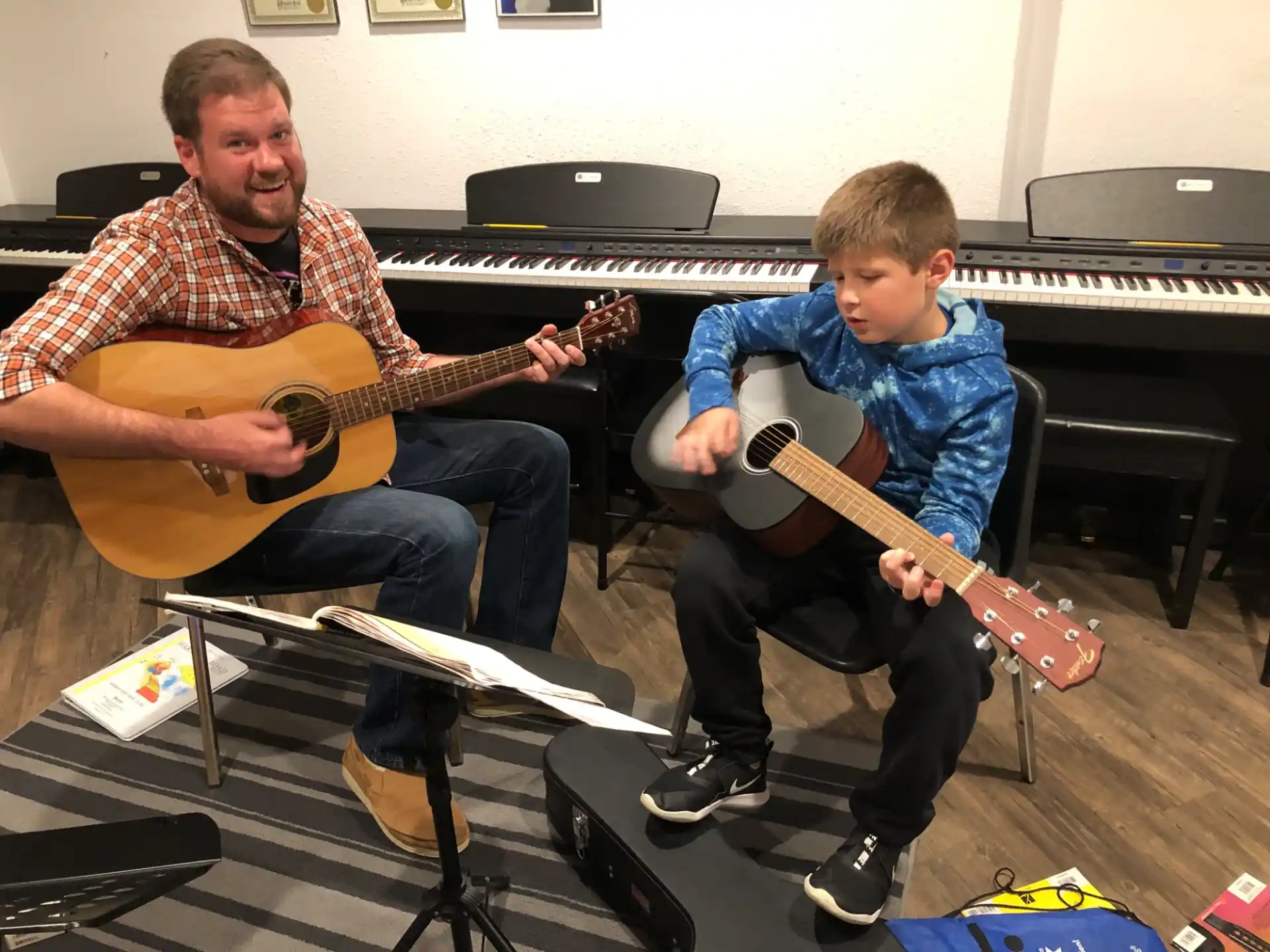 a person playing a guitar next to a boy playing a piano