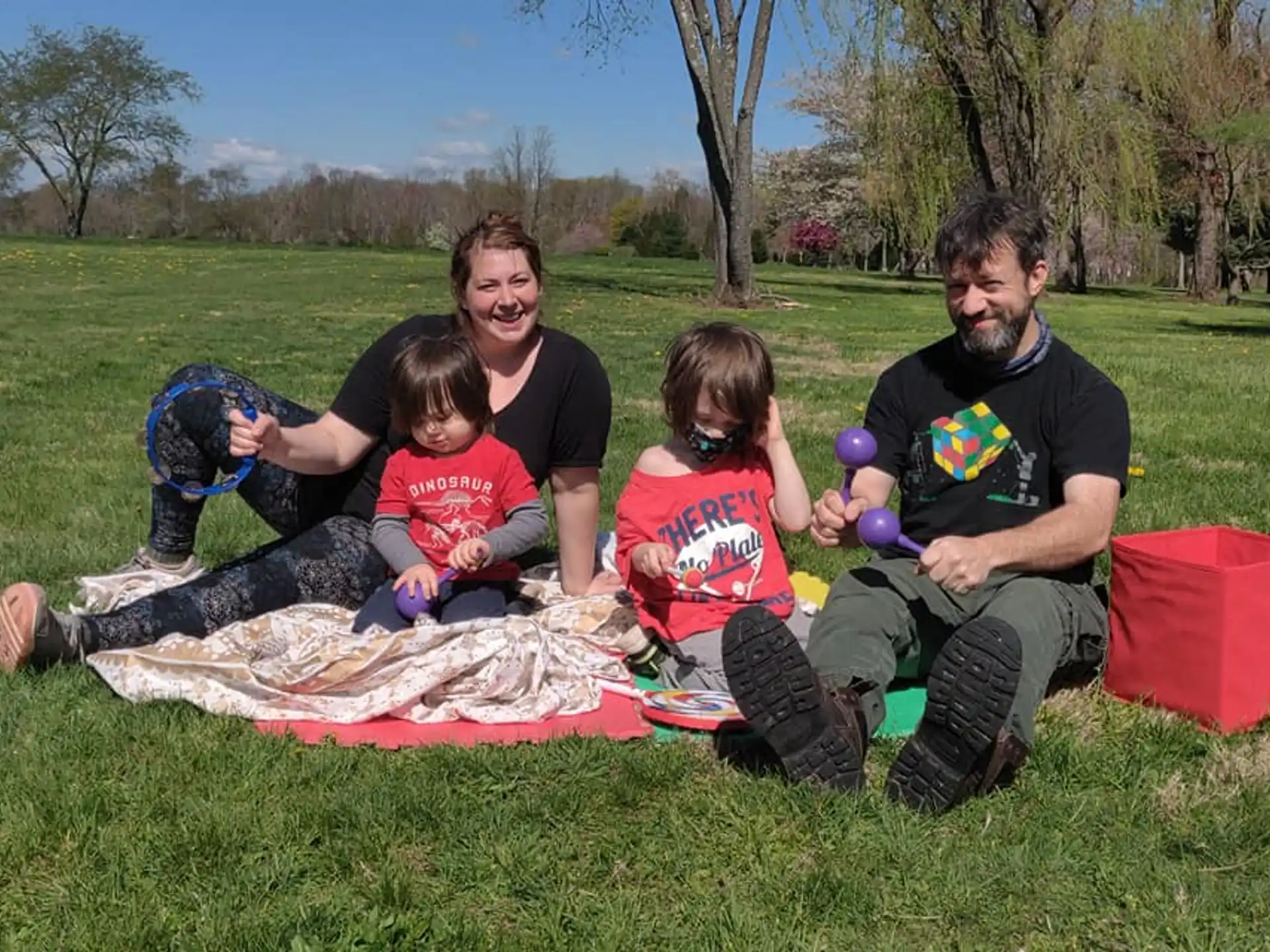 a group of people sitting on a blanket in a grassy area