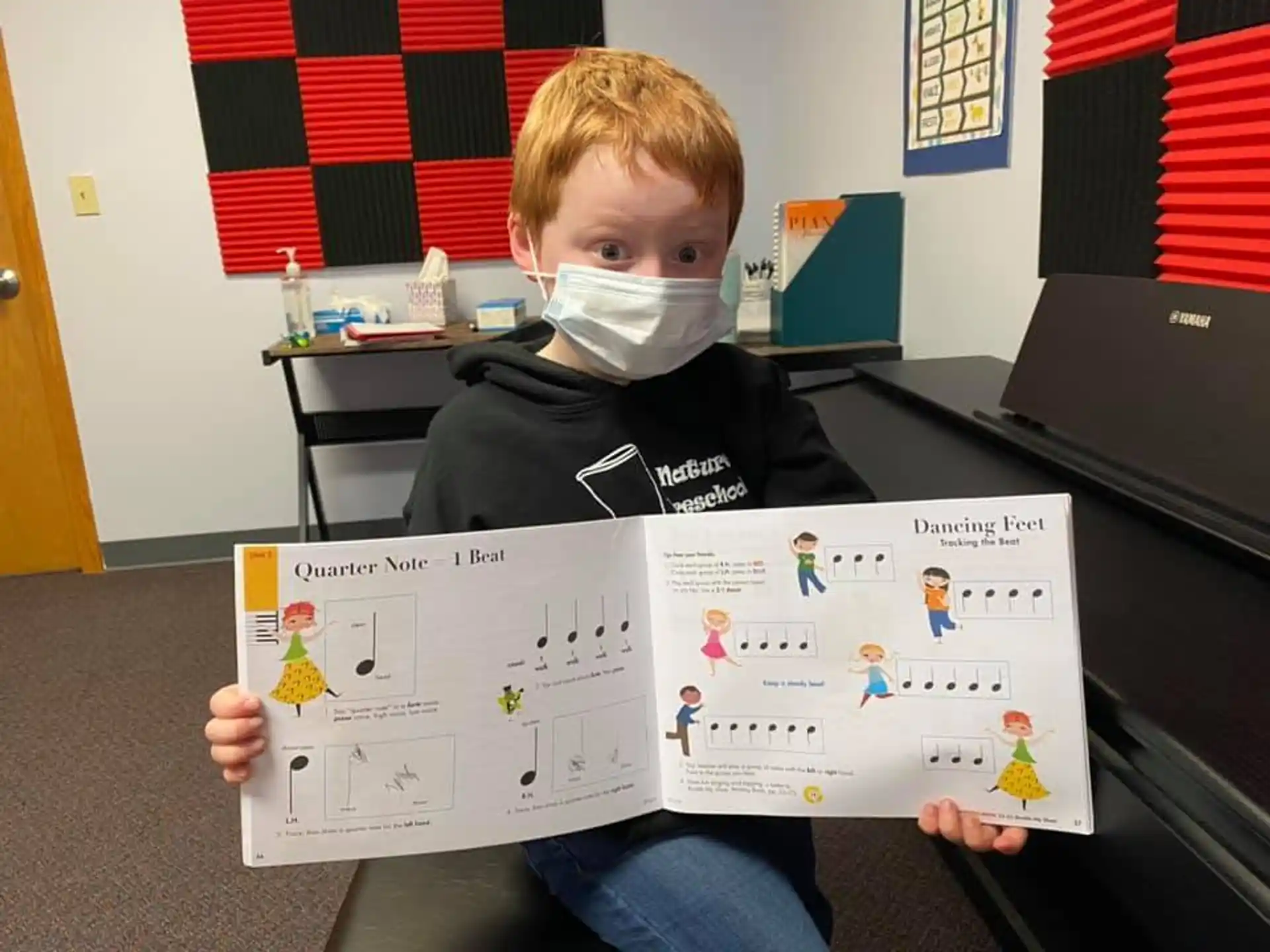 a boy holding a book and a drawing on a table