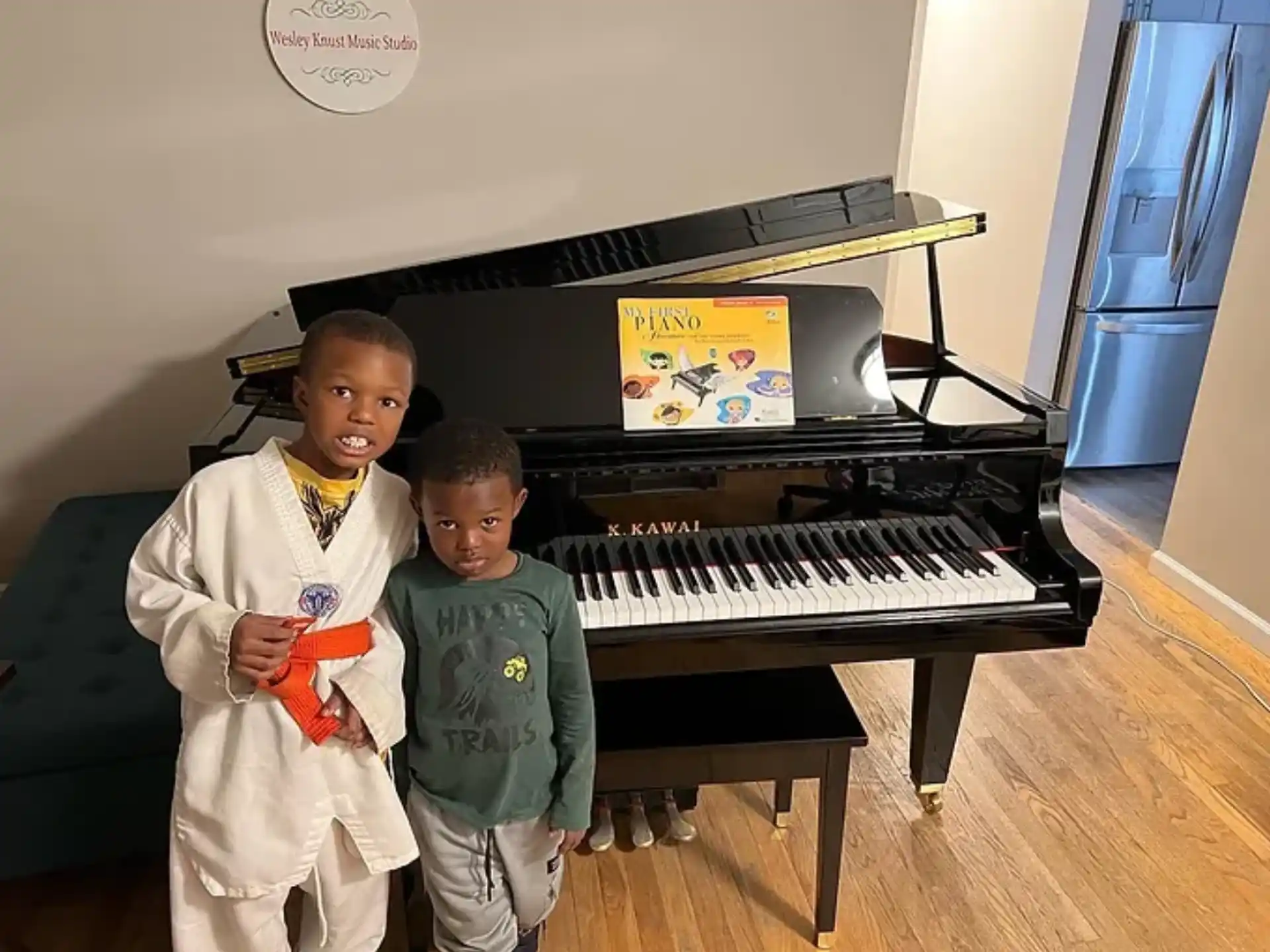 a couple of boys posing for the camera in front of a piano