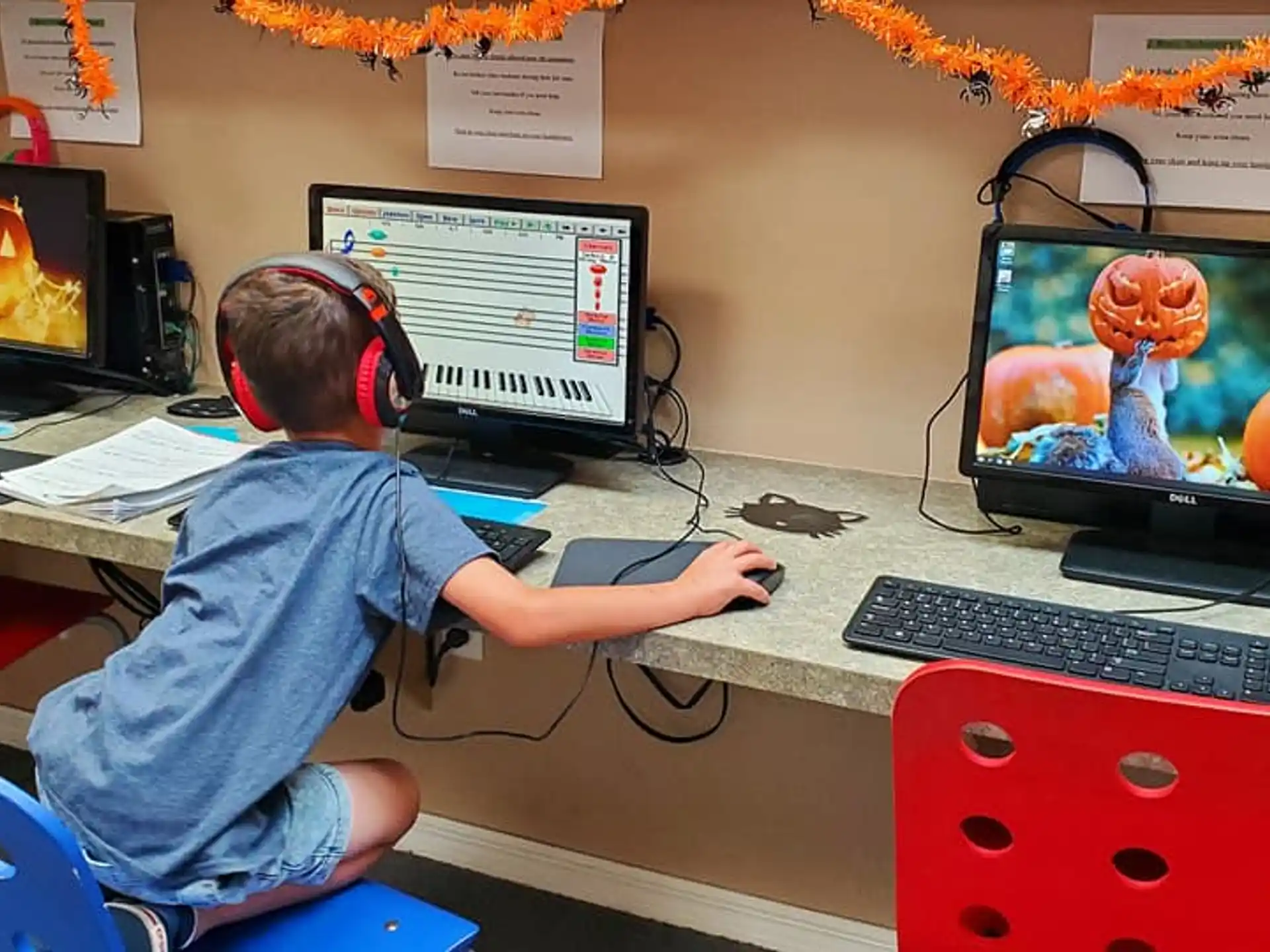 a boy sitting at a desk with multiple monitors