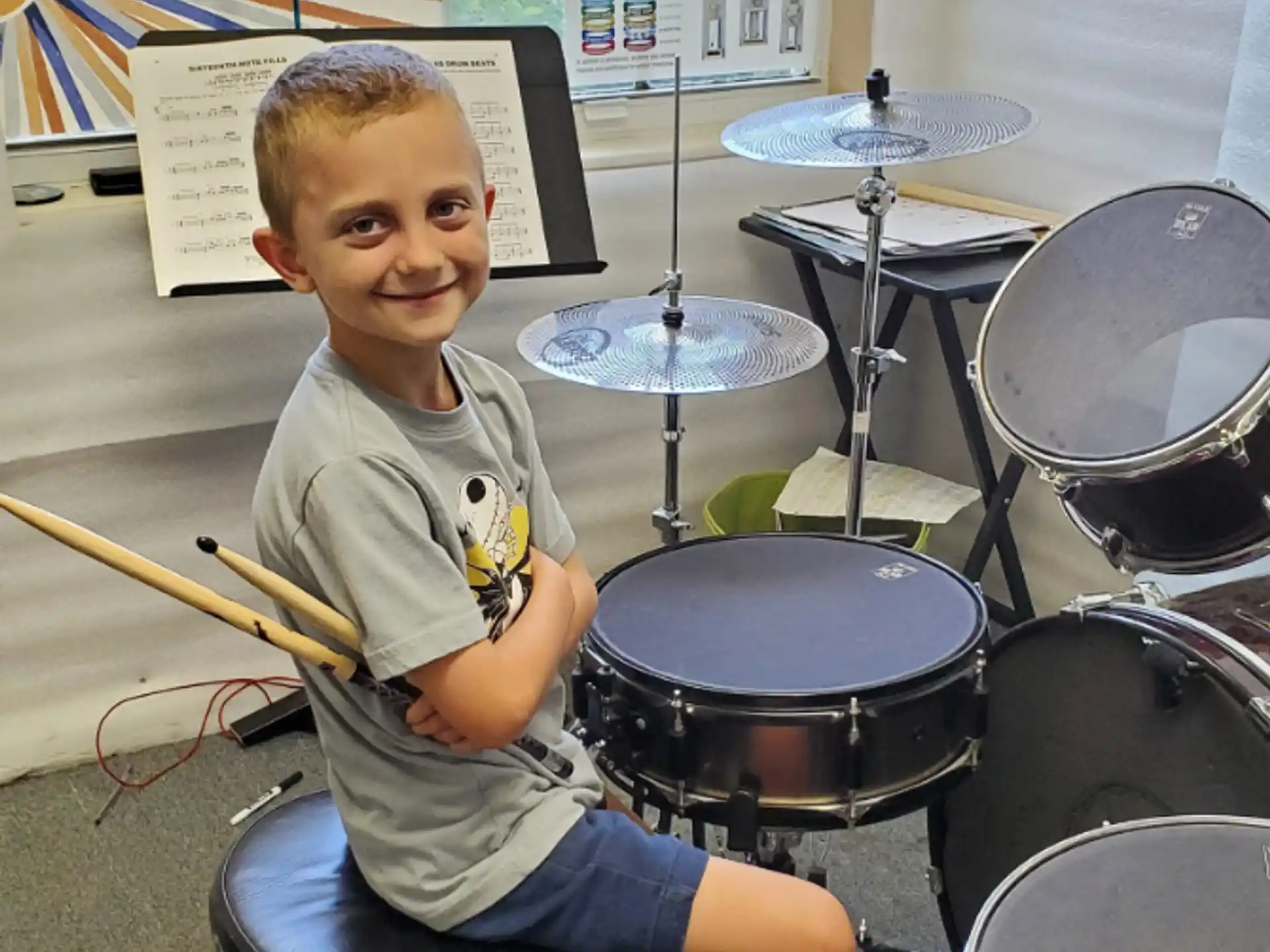 a boy sitting in front of a drum set