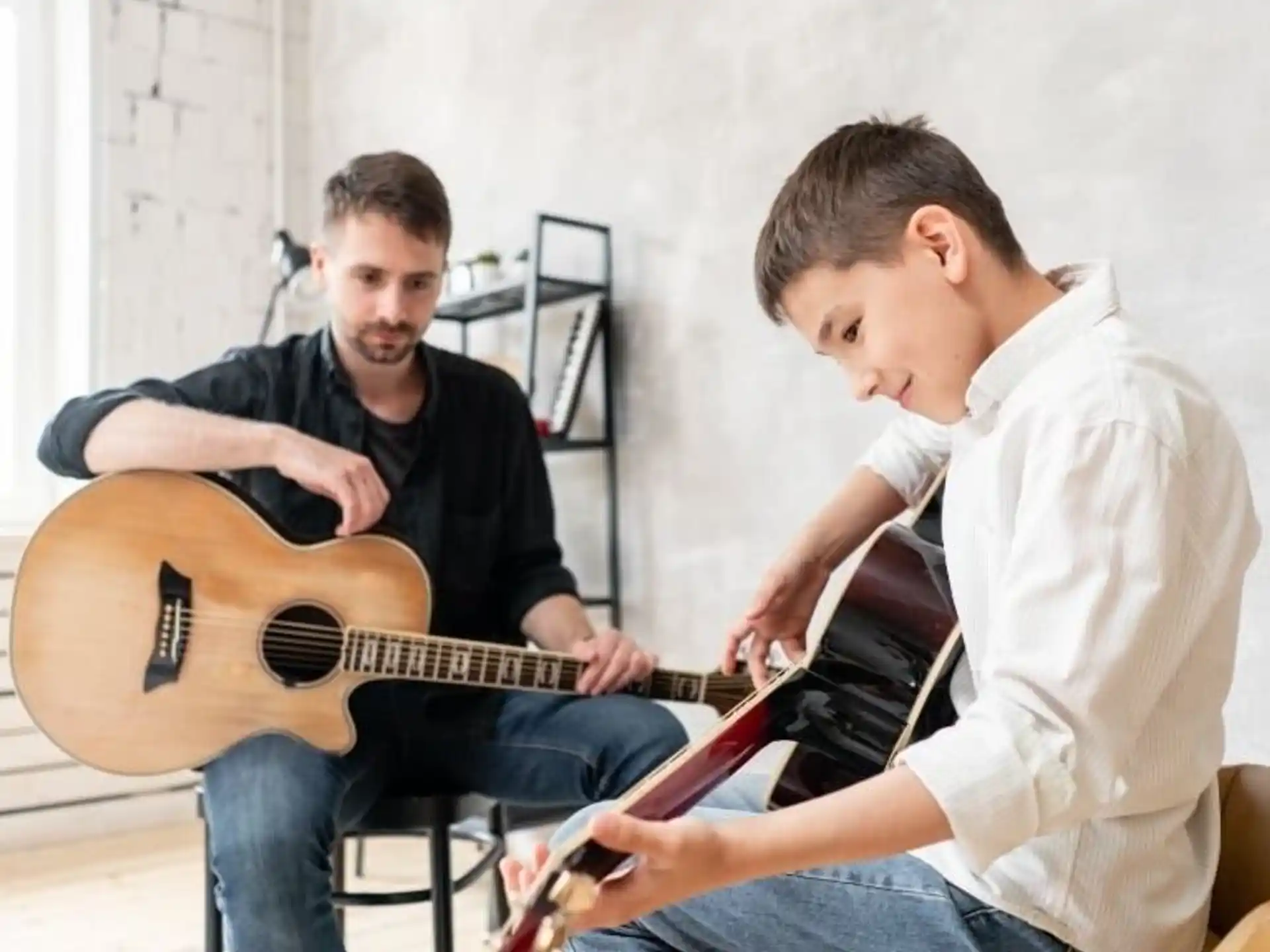 a man playing a guitar next to a man sitting on a chair