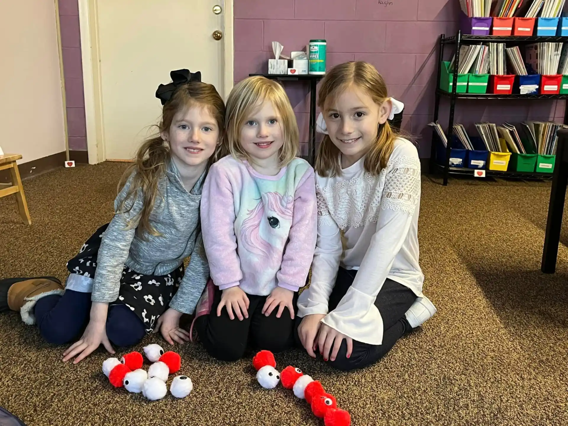 a group of girls sitting on the floor with toys