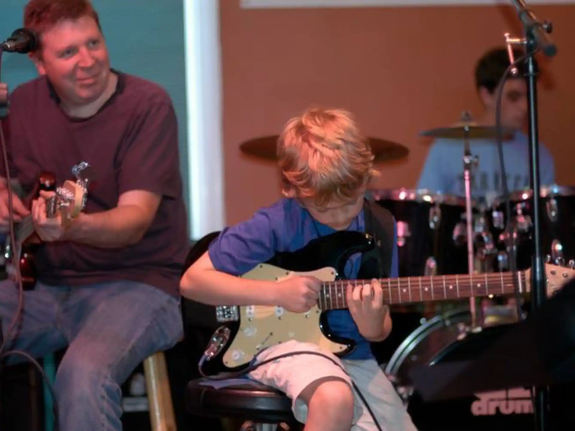 a man playing guitar next to a man playing a guitar