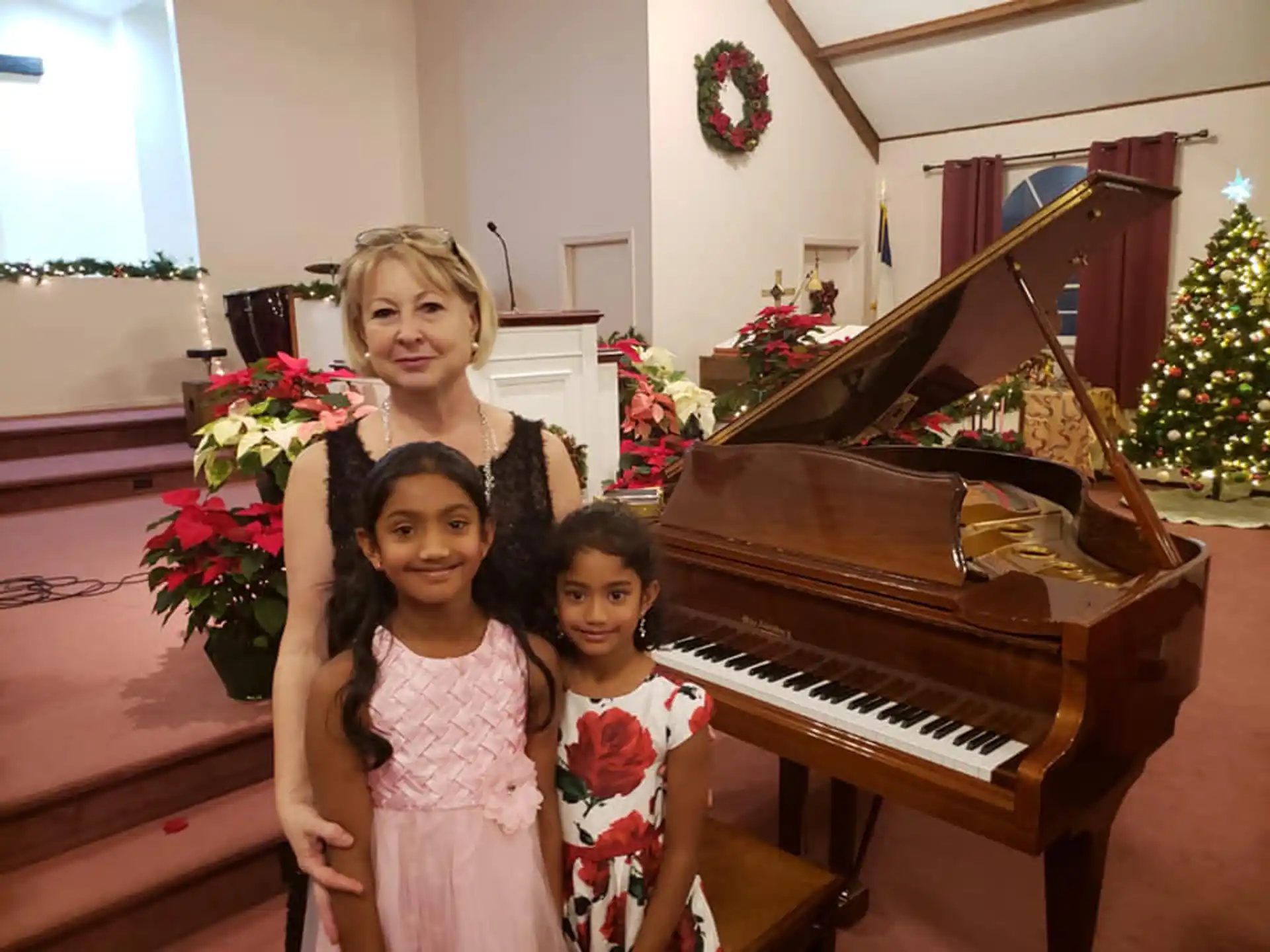 a couple of girls posing for a picture next to a piano