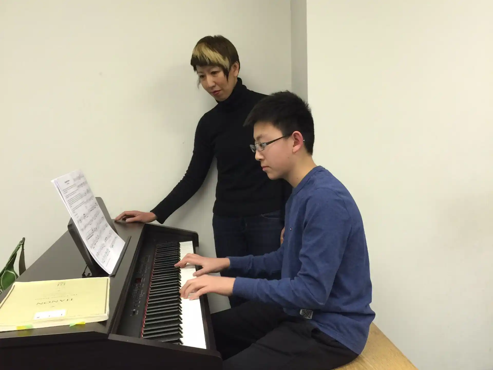 a person playing a piano with another man sitting at the piano
