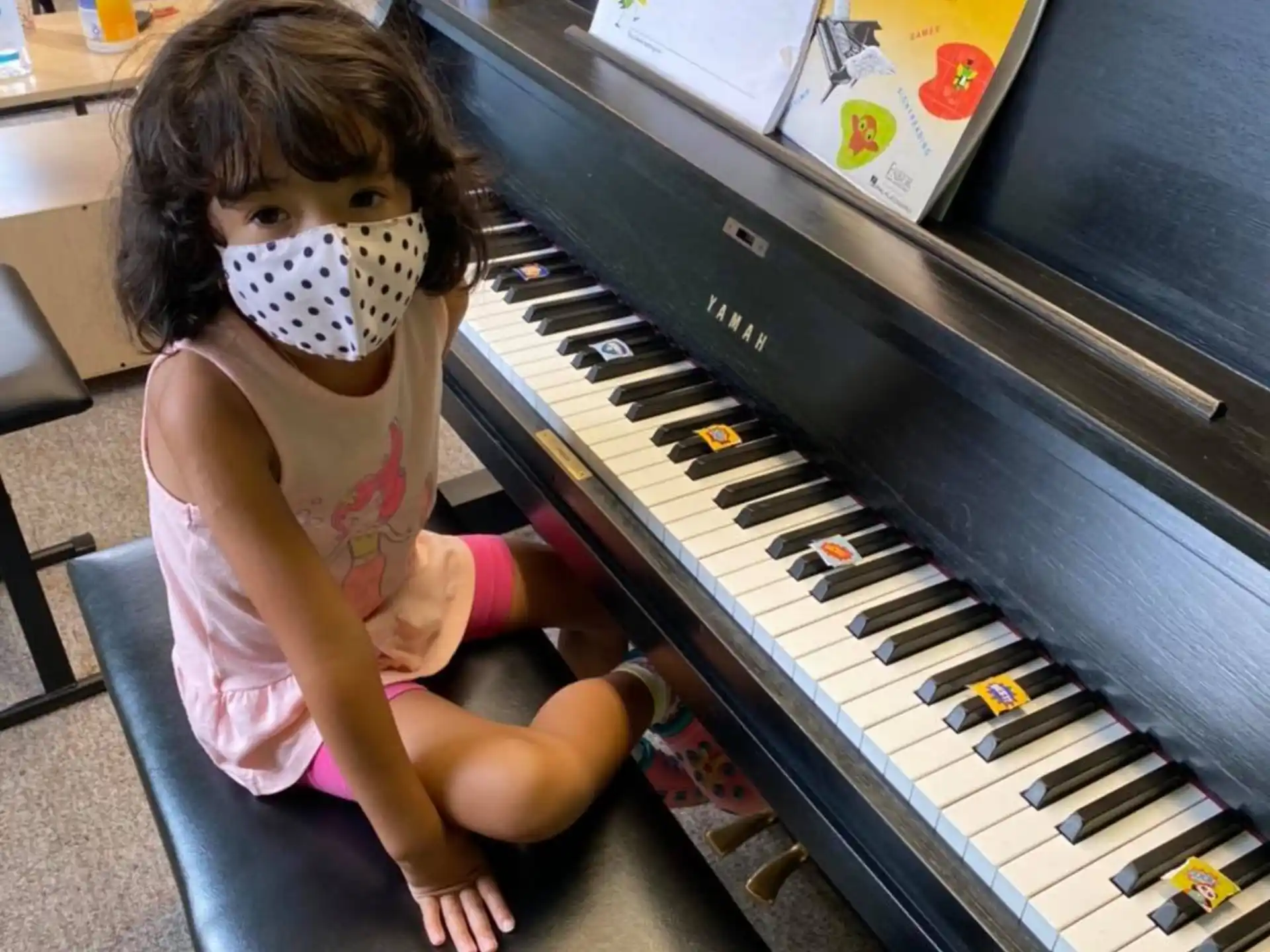 a girl sitting on a chair next to a piano