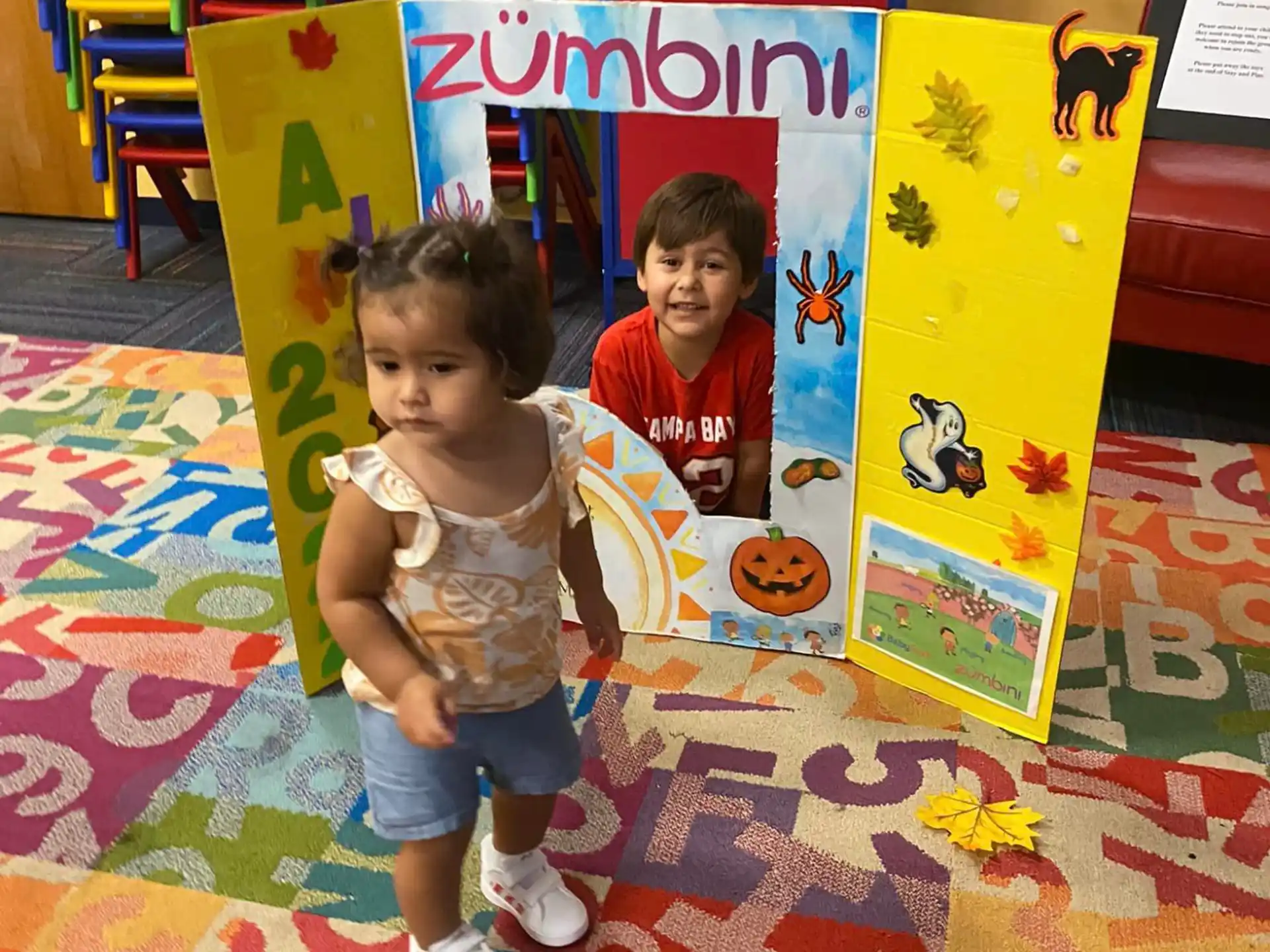 a couple of kids sitting on the floor in a room with a colorful floor and chairs