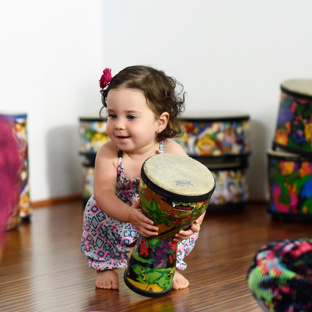 a little girl holding a drum