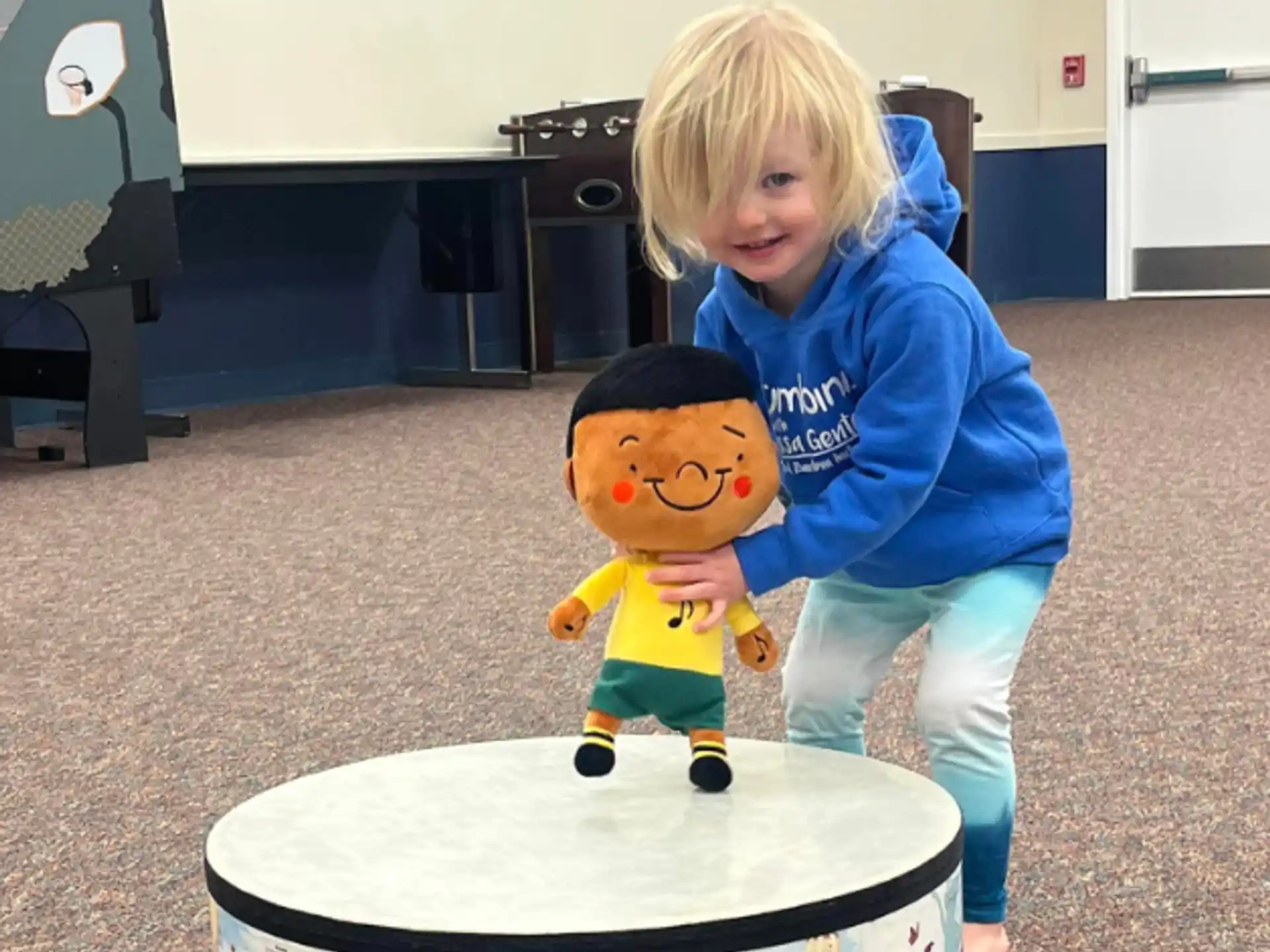 a child standing next to a stuffed toy