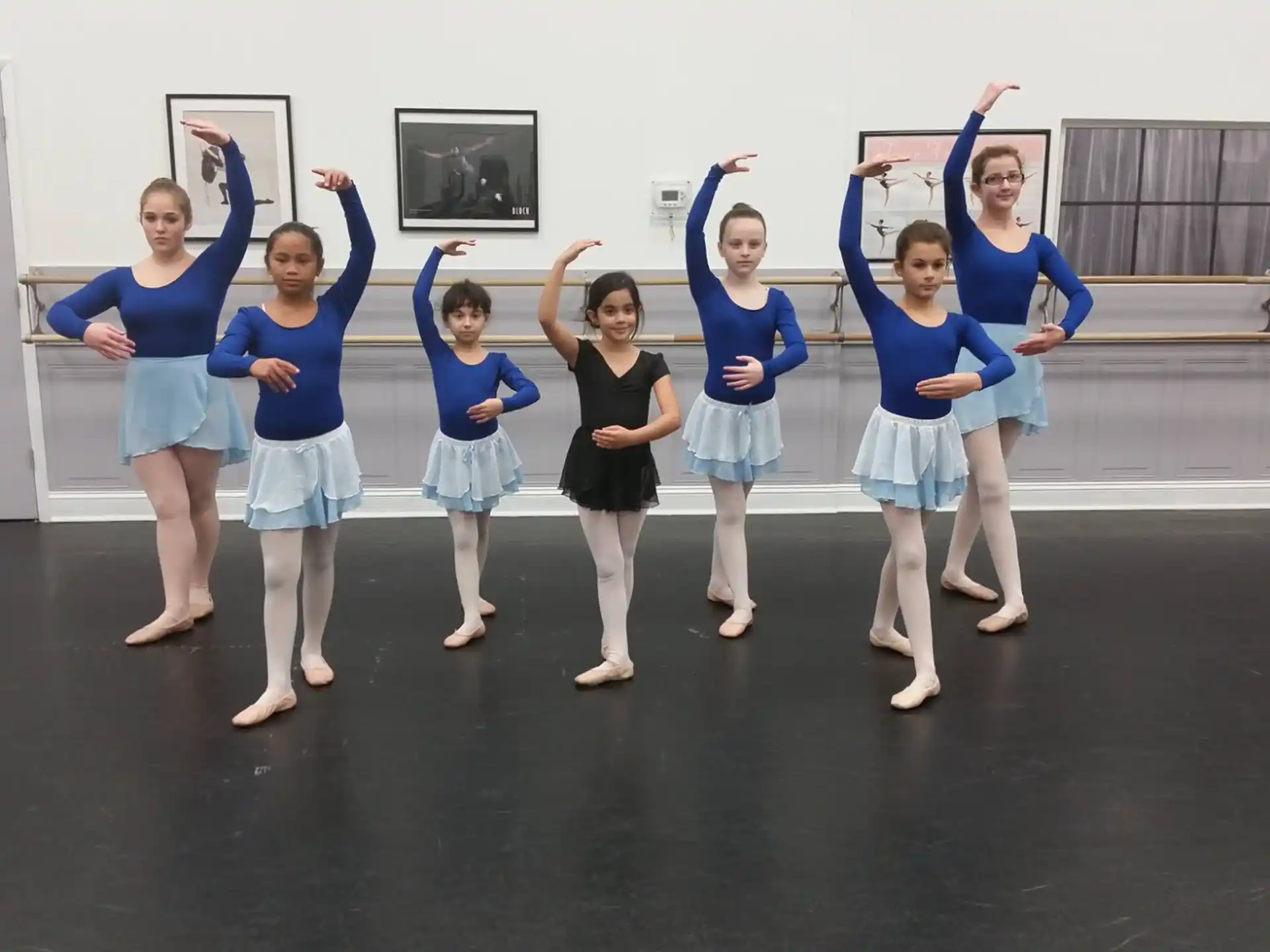 a group of girls in blue shirts and skirts with arms raised