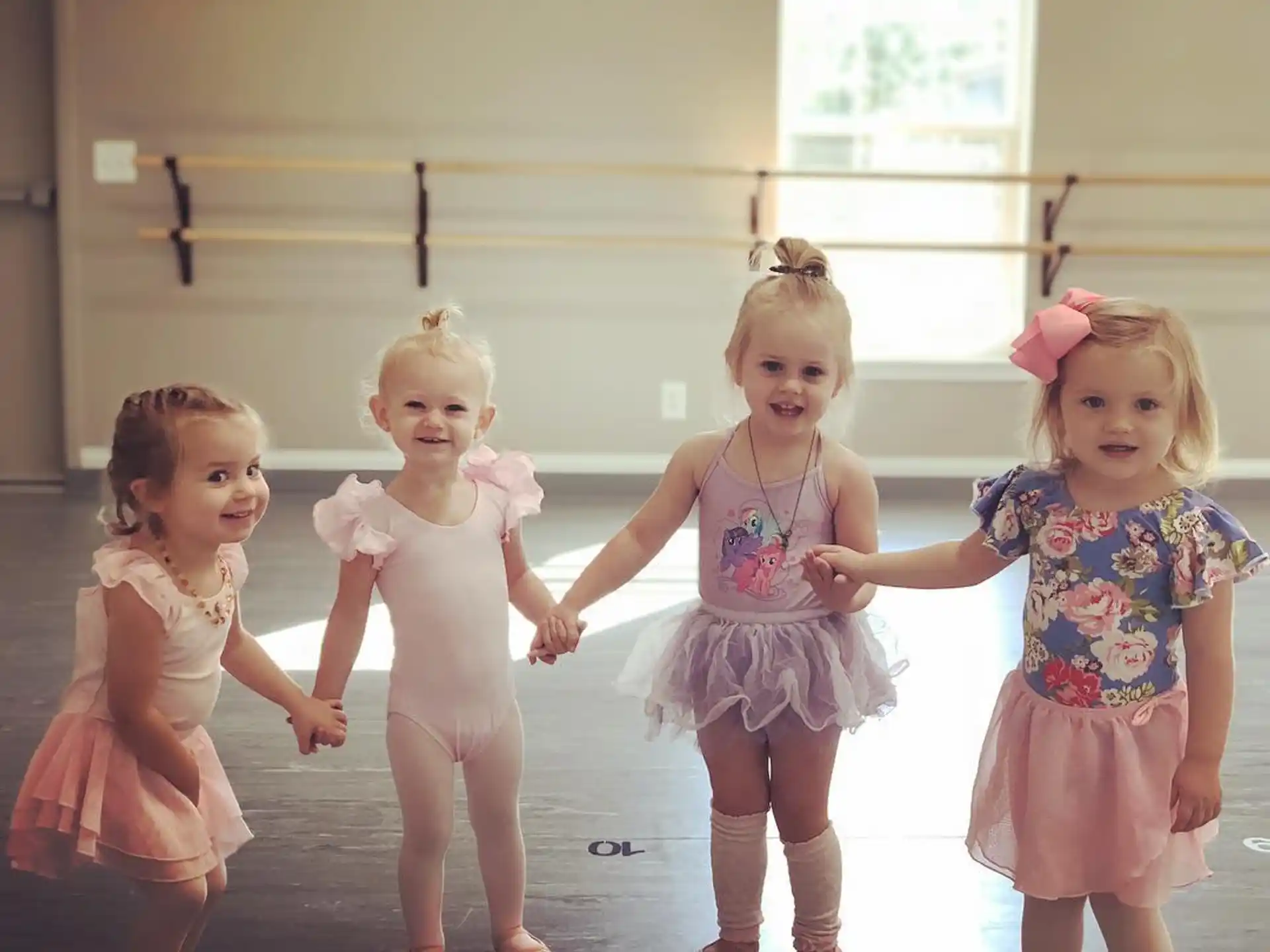 a group of girls wearing dresses and dancing on a stage