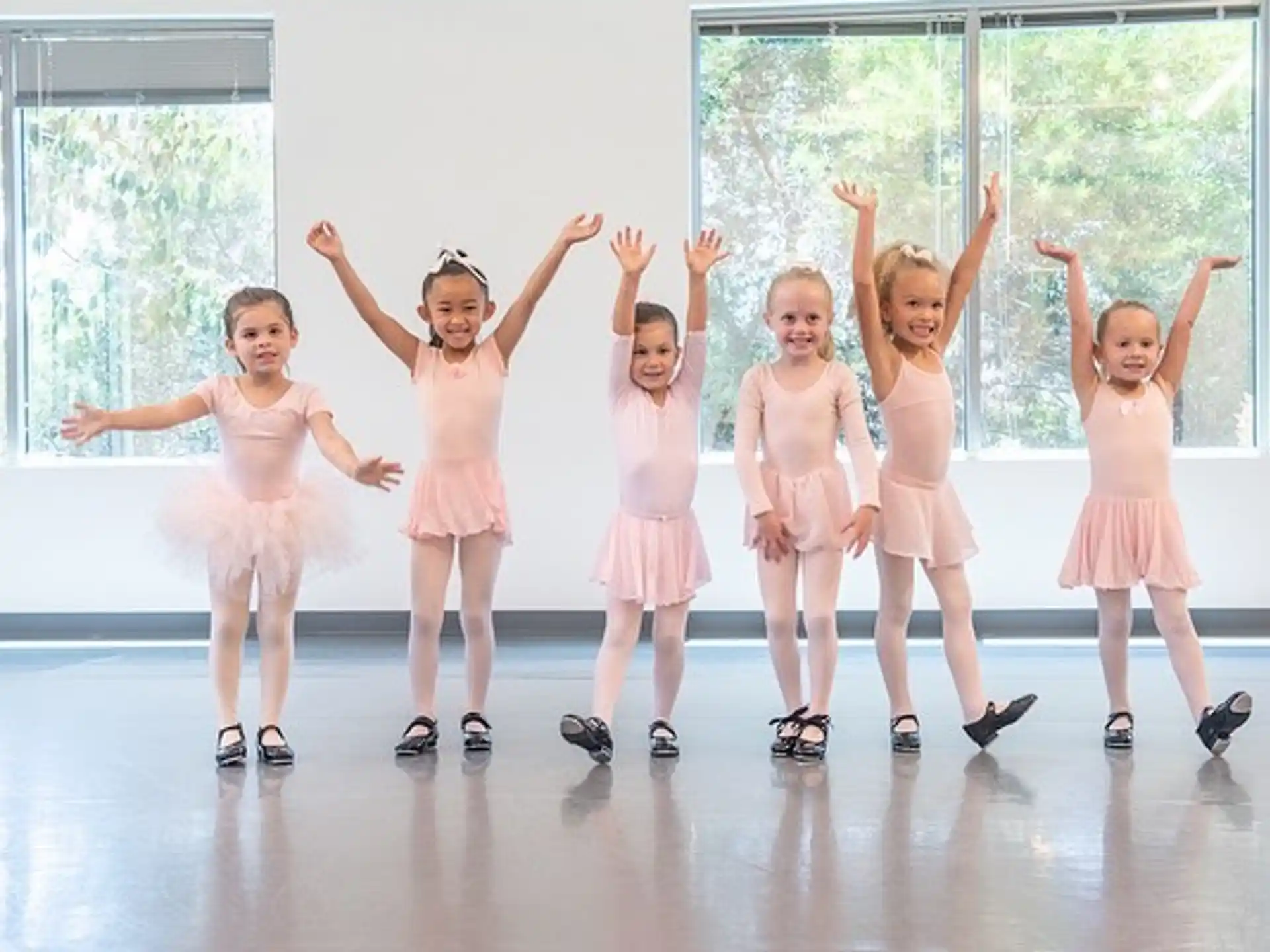 a group of girls wearing dresses and dancing in a room