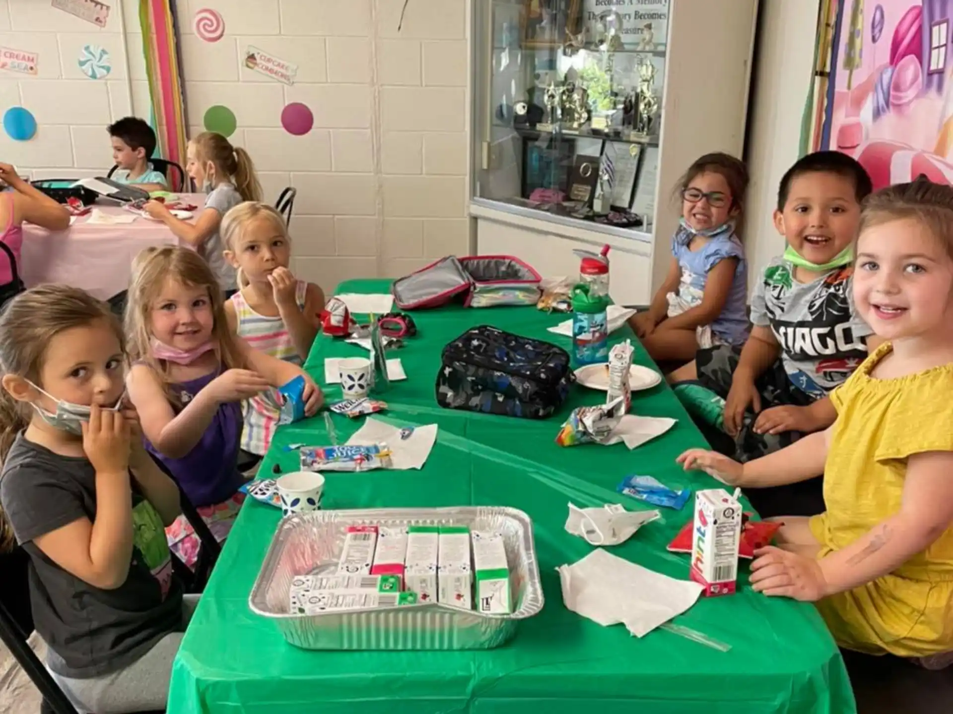 a group of children sitting at a table with toys