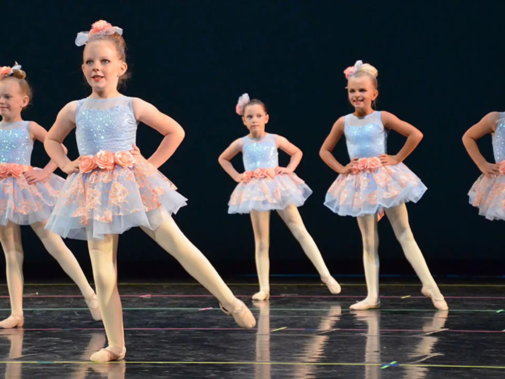 a group of girls in dresses on a stage