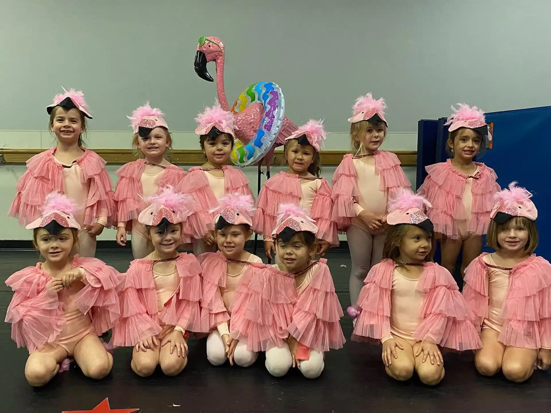 a group of children wearing pink and white dresses and holding balloons