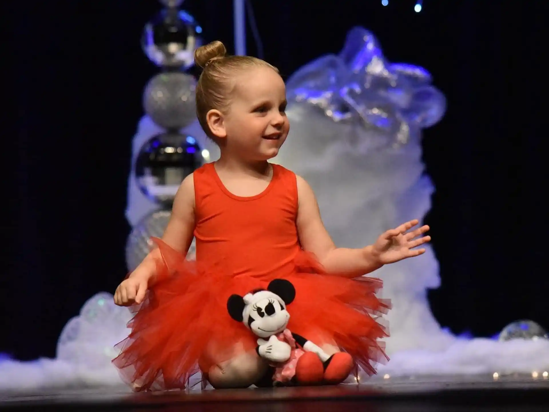 a baby in a dress holding a stuffed animal