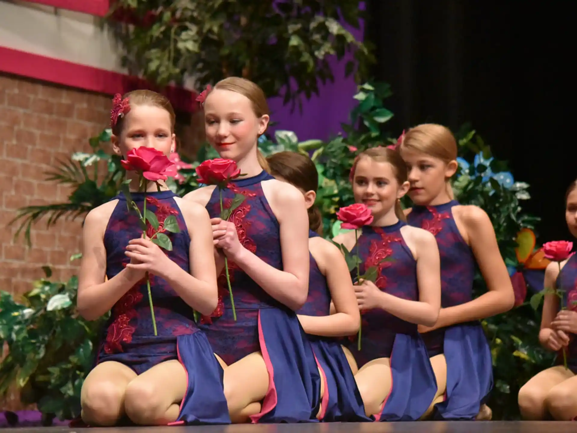 a group of girls in dresses holding flowers