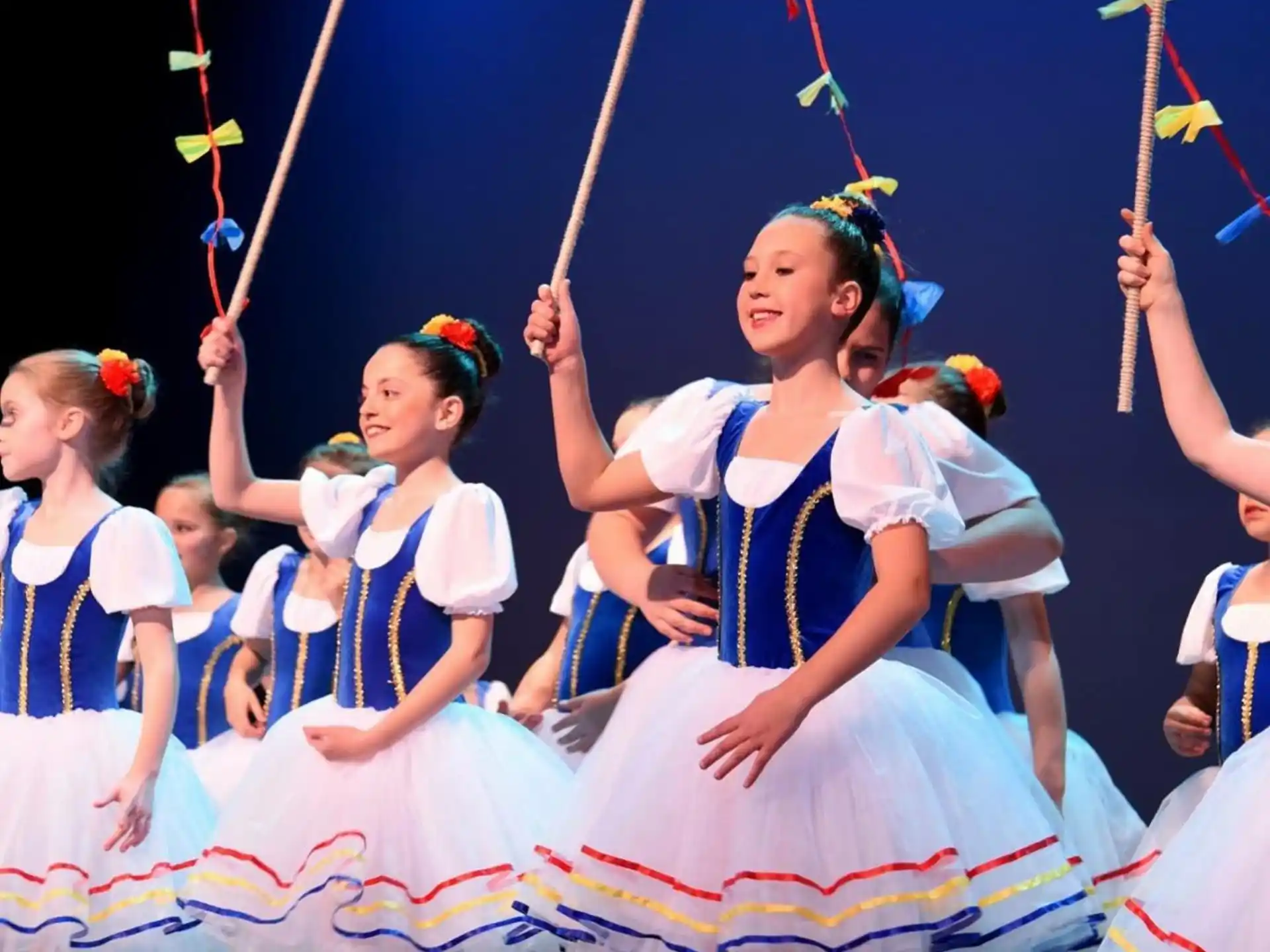 a group of girls in dresses holding flags
