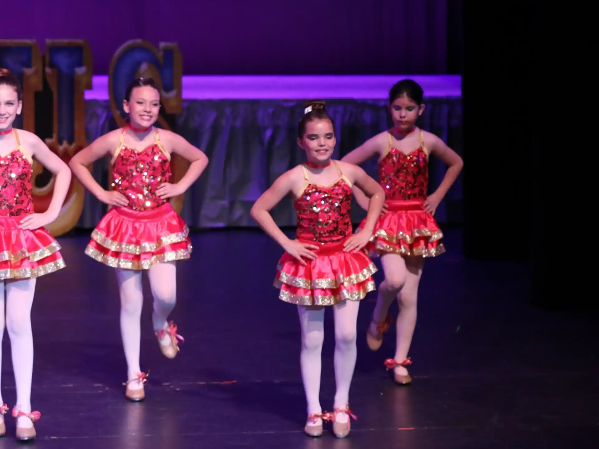 a group of women in red and white dresses on a stage