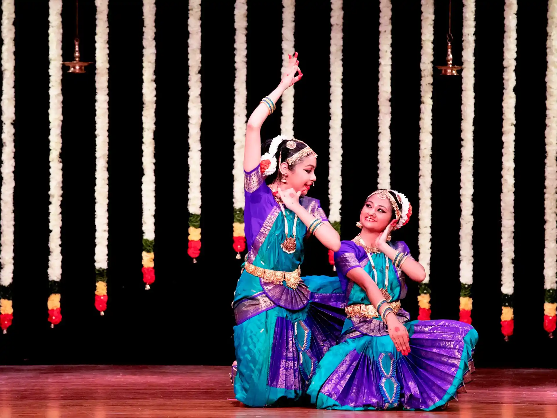 a group of women in traditional dress dancing on a stage