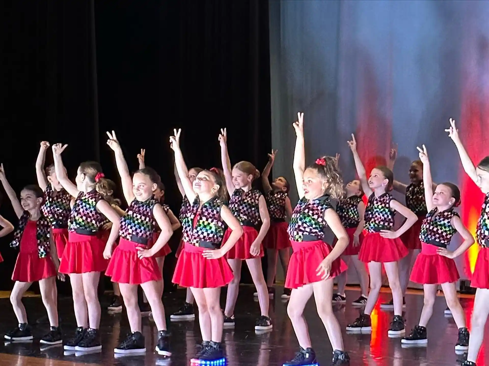 a group of girls in red and white dresses on a stage
