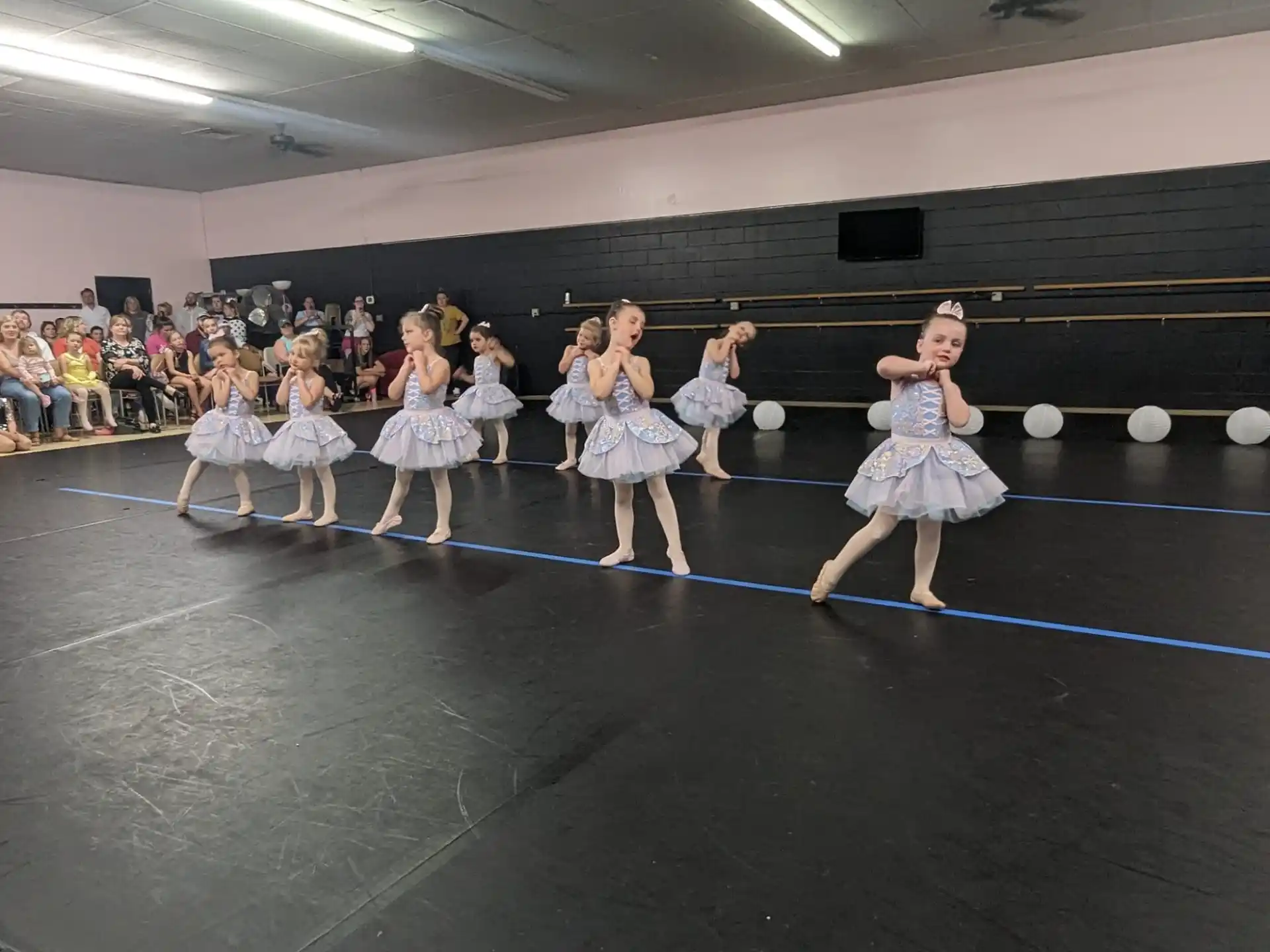 a group of girls in dresses dancing on a stage
