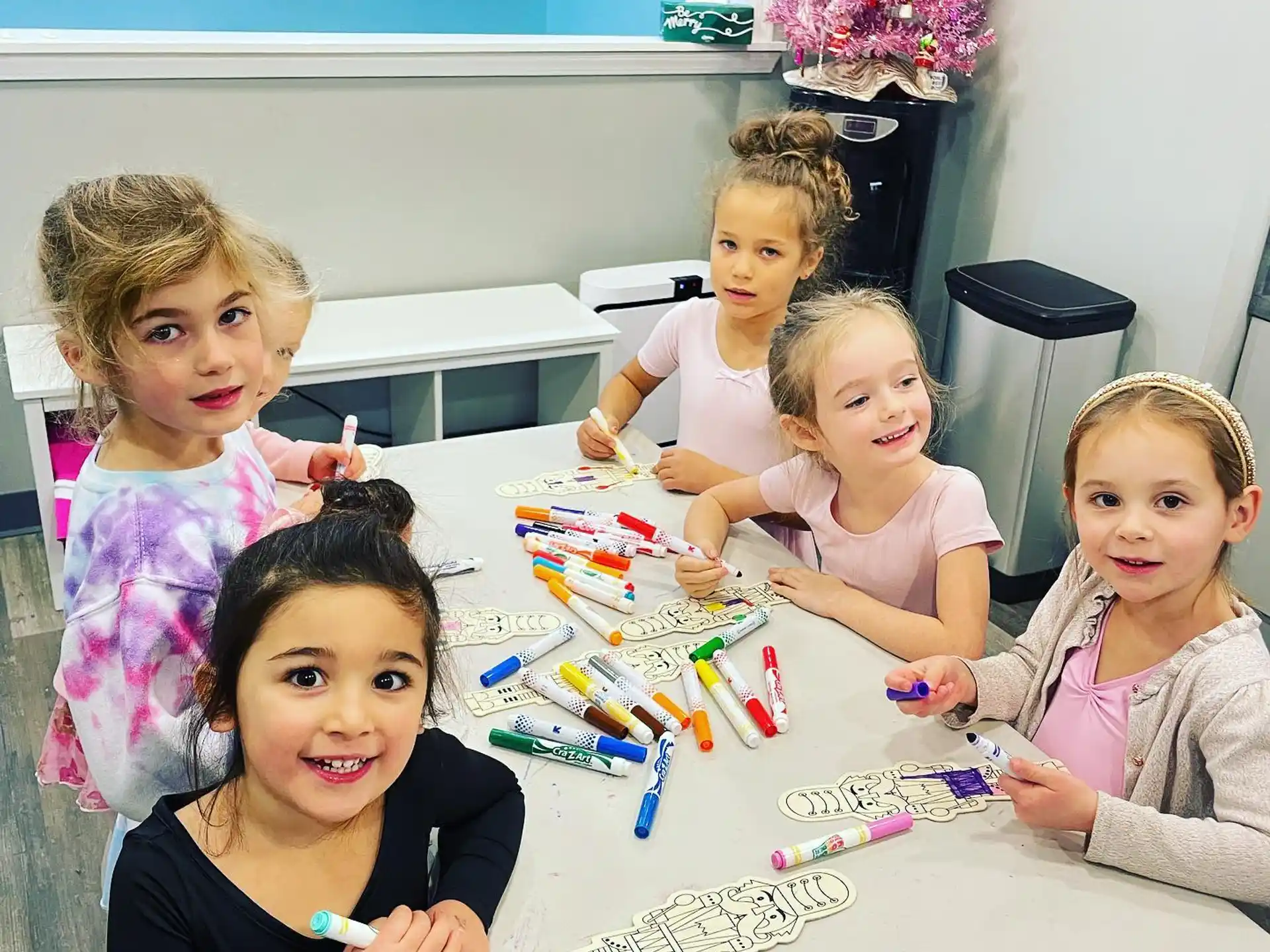a group of children sitting at a table with a toy