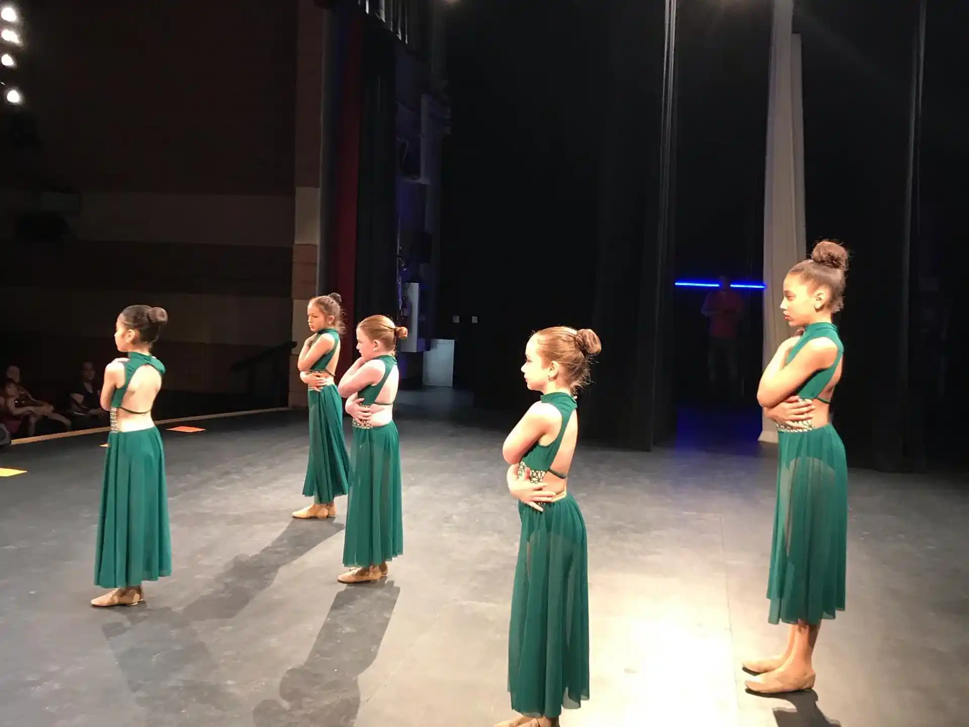 a group of girls in dresses on a stage