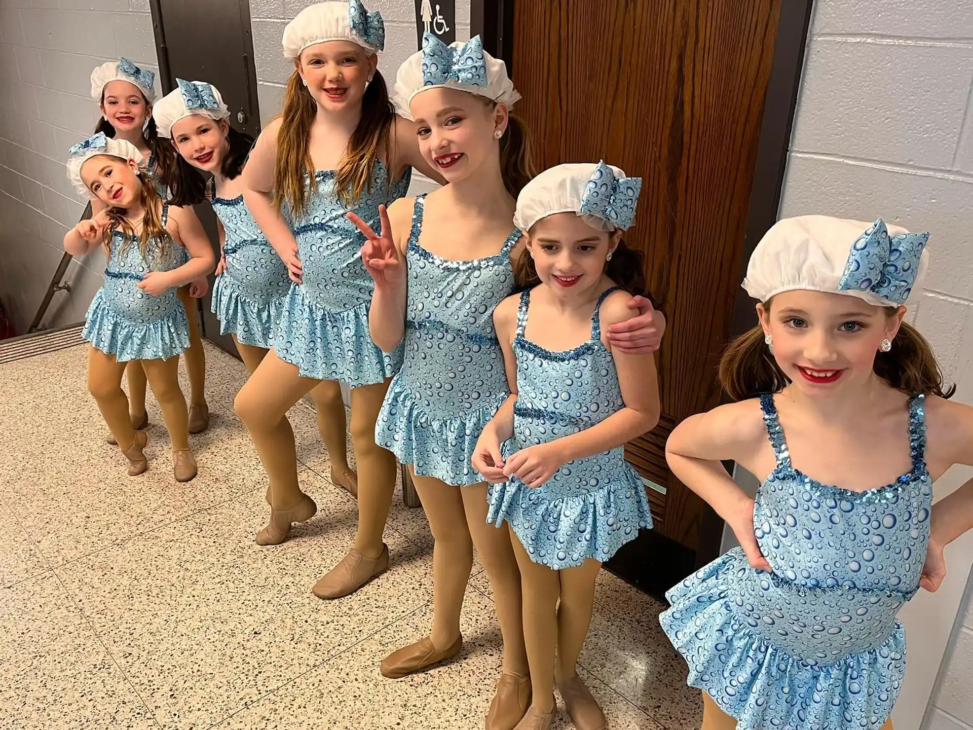 a group of girls wearing blue dresses and white hats