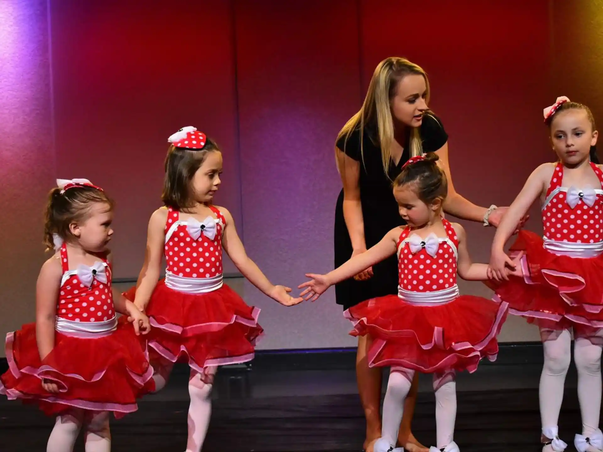 a group of girls in red and white dresses dancing on a stage