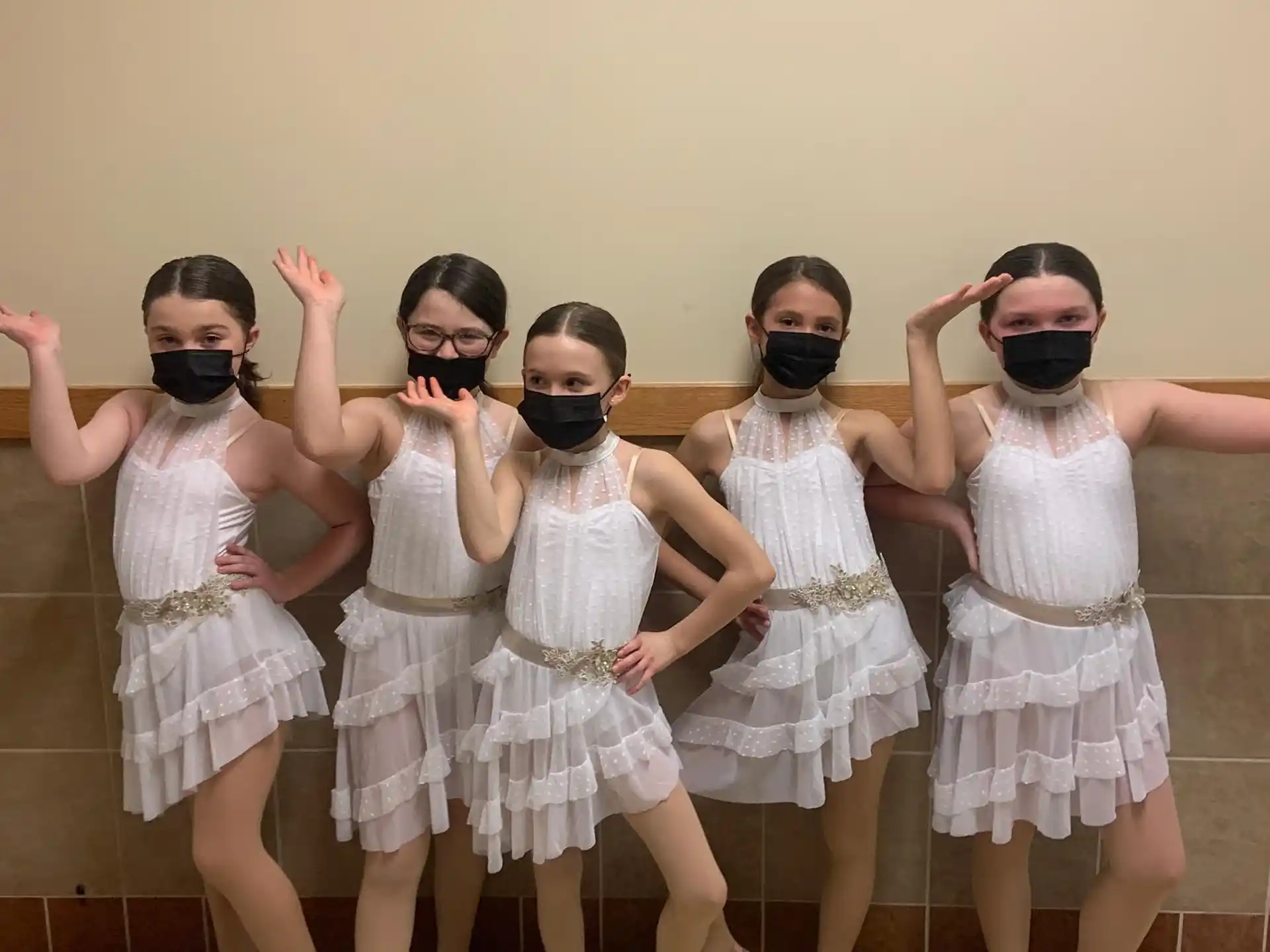 a group of girls wearing white dresses and posing for a photo