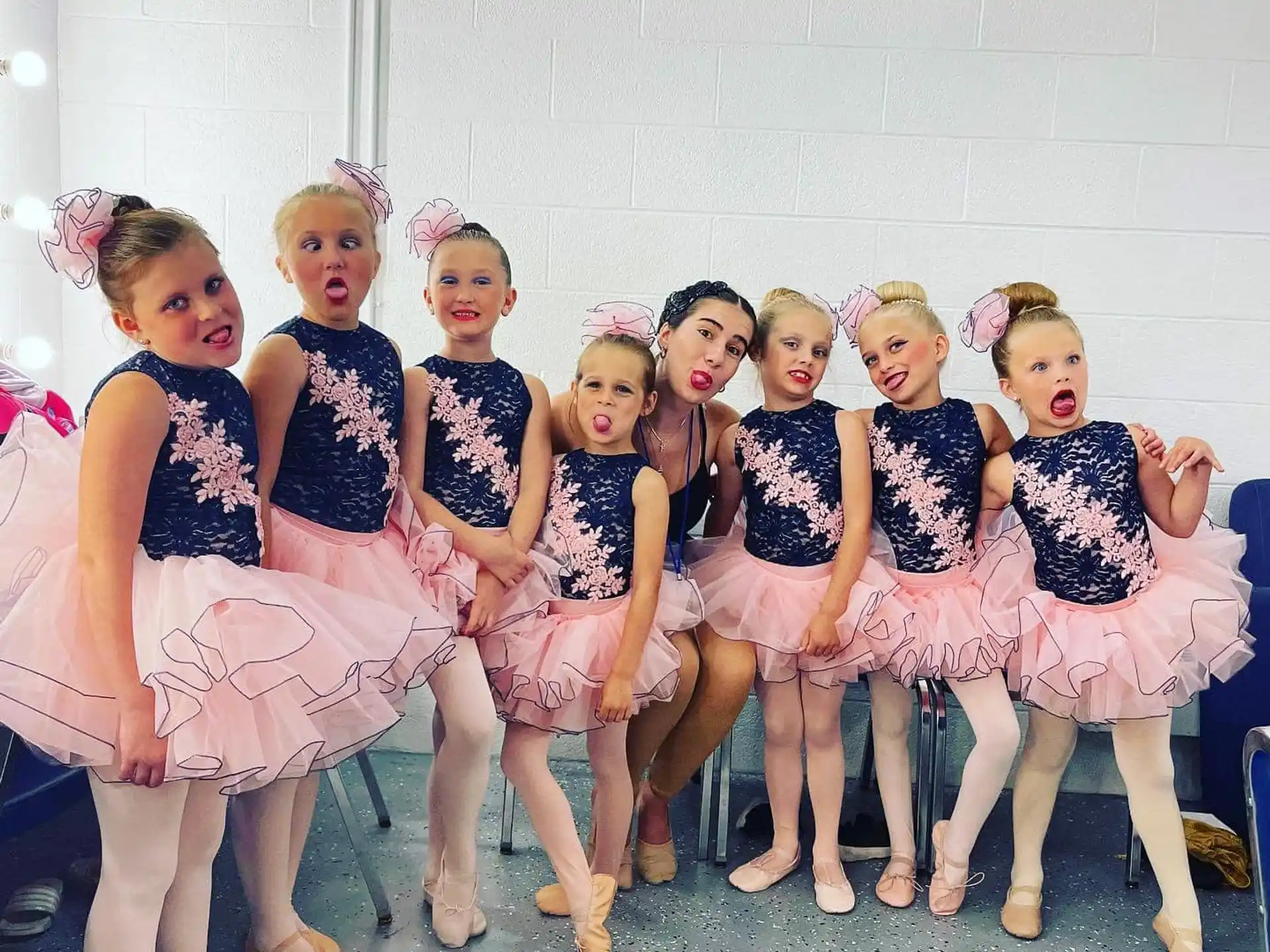 a group of girls in dresses and skirts posing for a photo