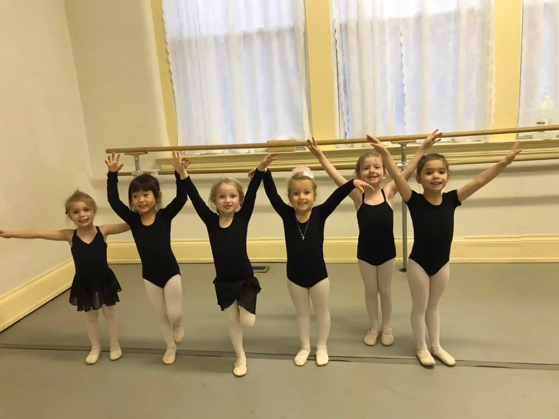 a group of girls in black ballet outfits posing for a photo