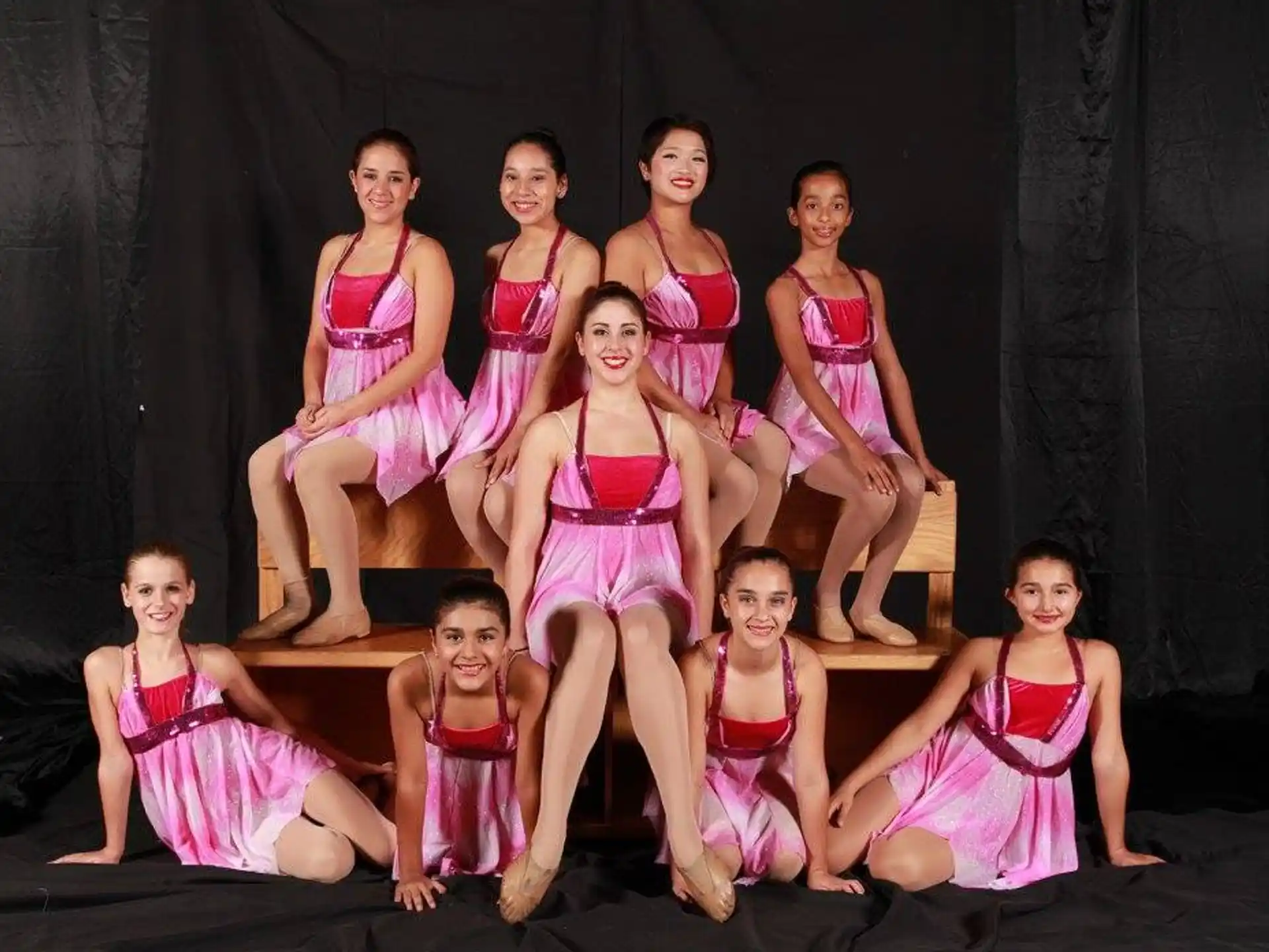 a group of girls in pink and white dresses on a stage