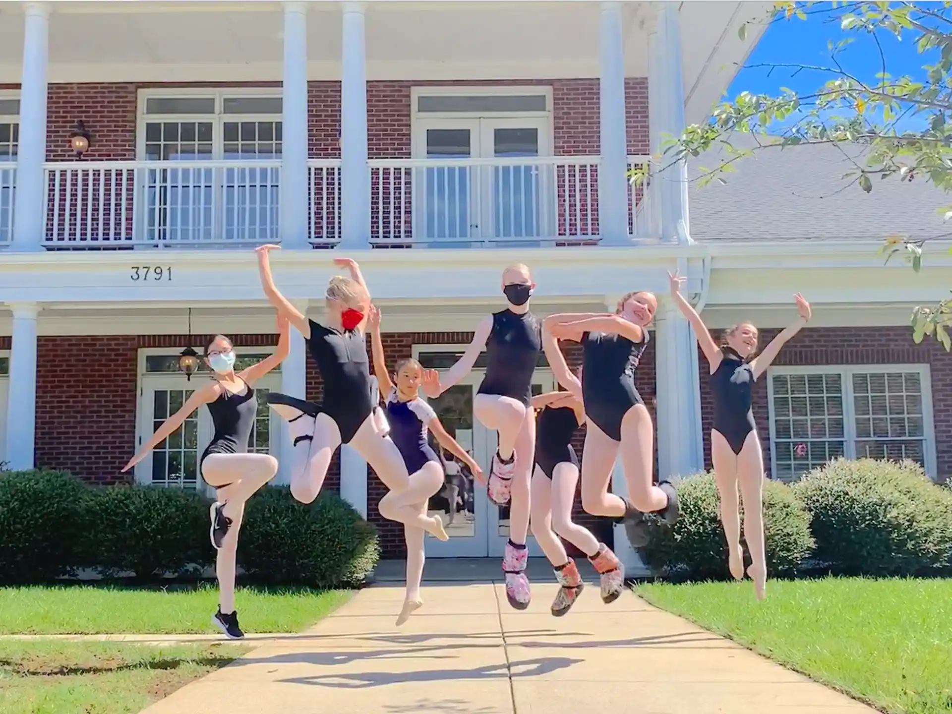 a group of people jumping in the air in front of a house