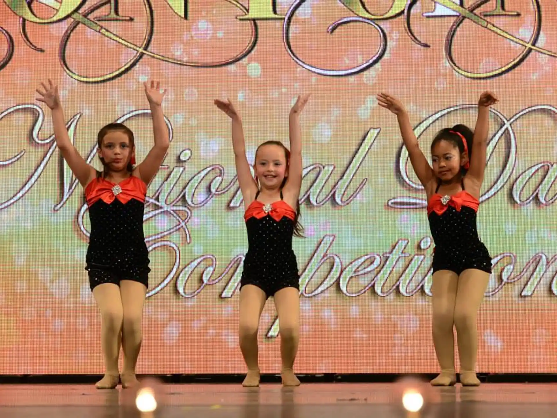 a group of girls in black and red uniforms on a stage