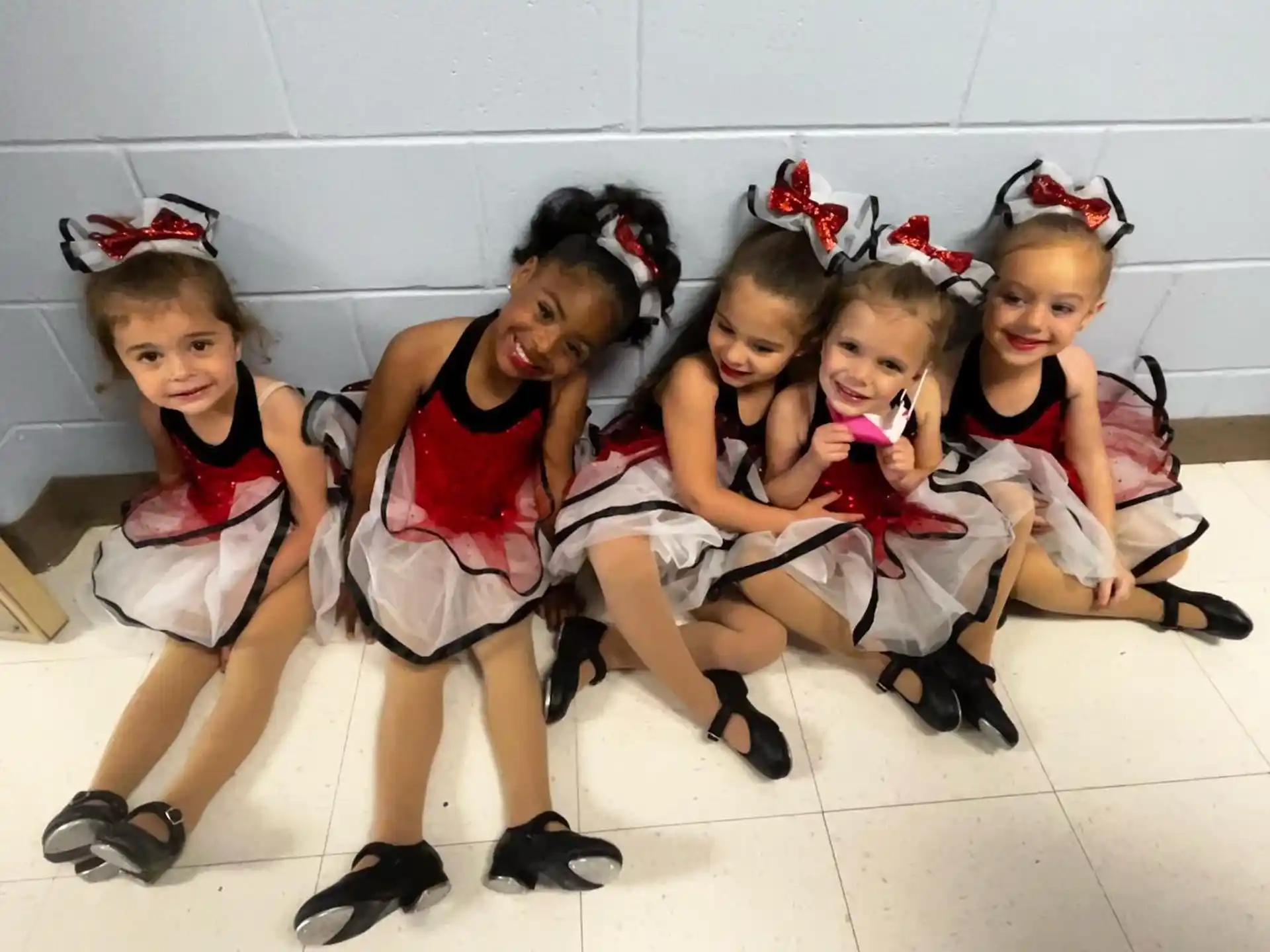 a group of girls wearing red and white dresses and sitting on the floor