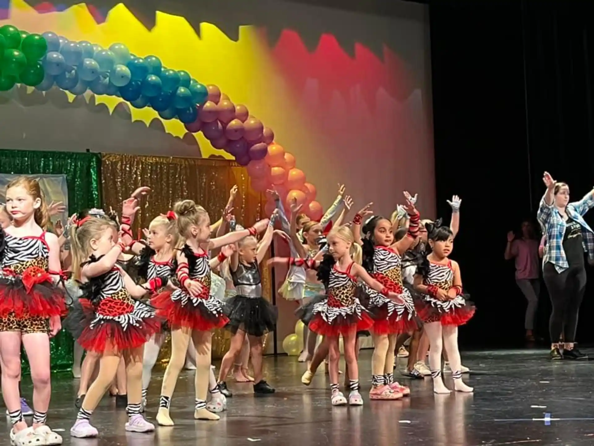 a group of girls in red and black dresses on a stage